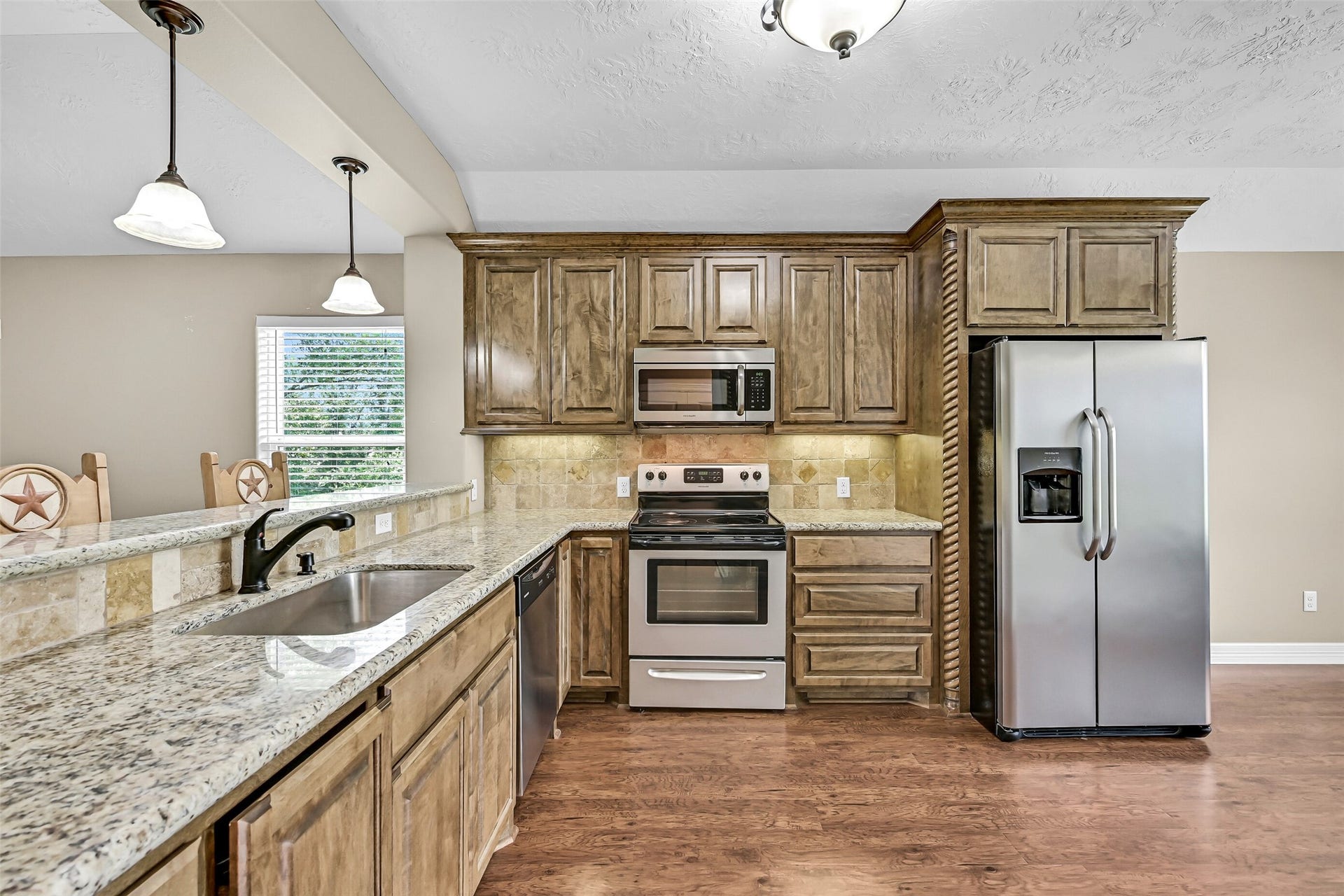 11930 Bastrop Beach Road, Angleton, TX 77515 Designed to be both beautiful and functional, the kitchen features custom cabinetry, granite countertops, a tumbled stone backsplash, stainless steel appliances, undermount sink, bartop seating, and generous prep space for everything from everyday meals to weekend gatherings.