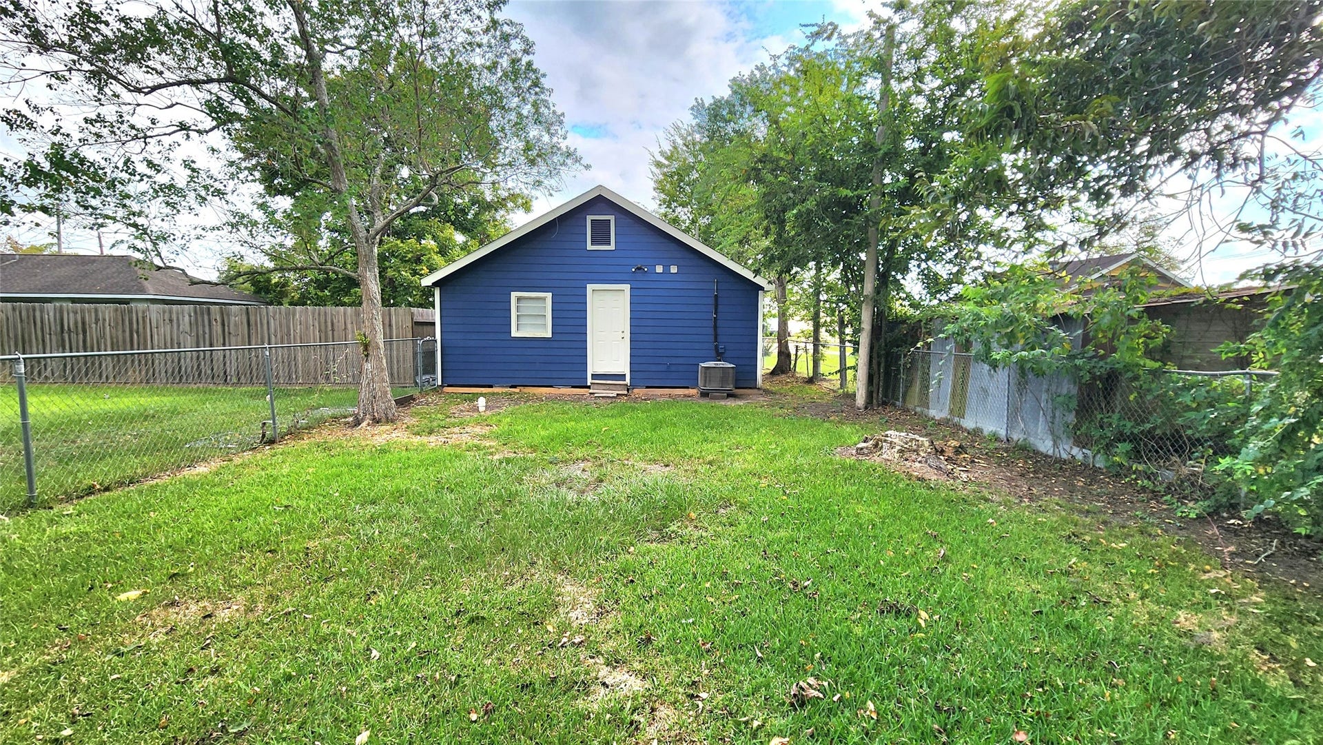 419 N Parrish Street, Angleton, TX 77515 Fenced backyard with open lawn and mature trees.