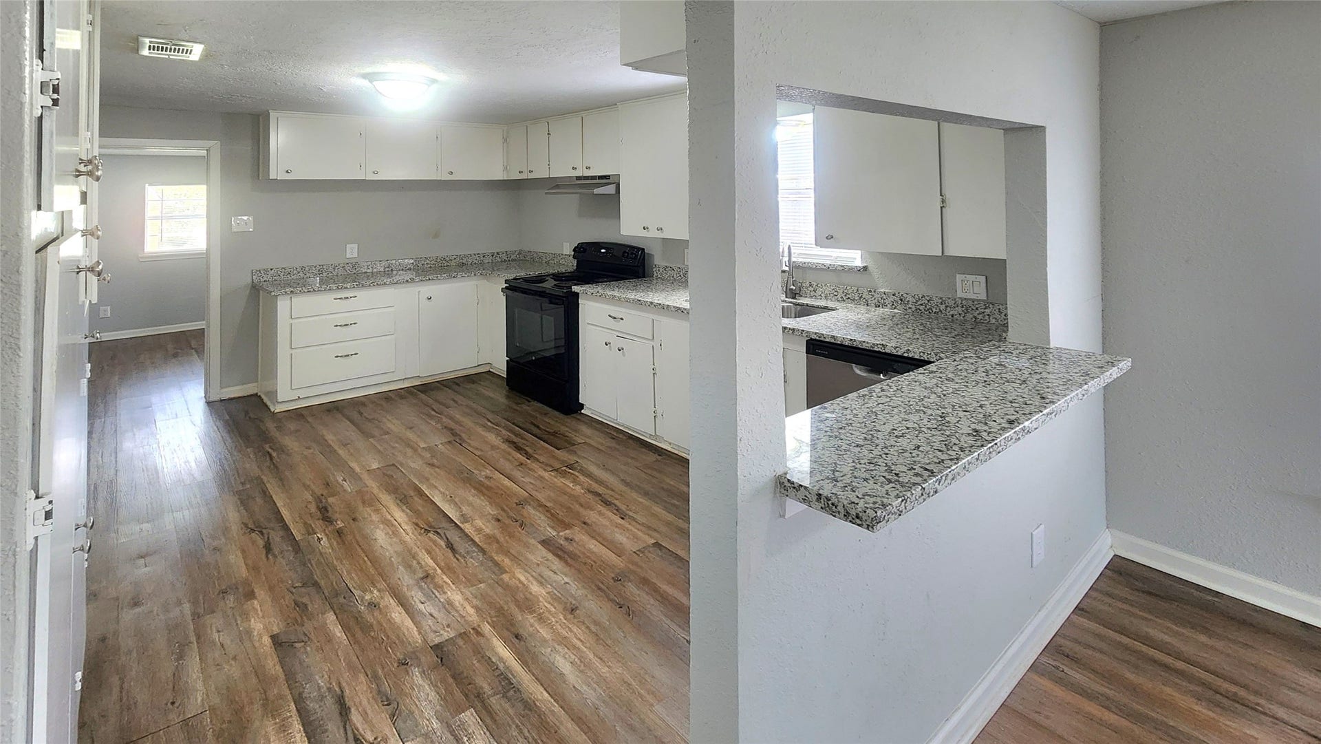 419 N Parrish Street, Angleton, TX 77515 Refreshed kitchen with white cabinetry, granite countertops, and a pass-through opening to the living area.