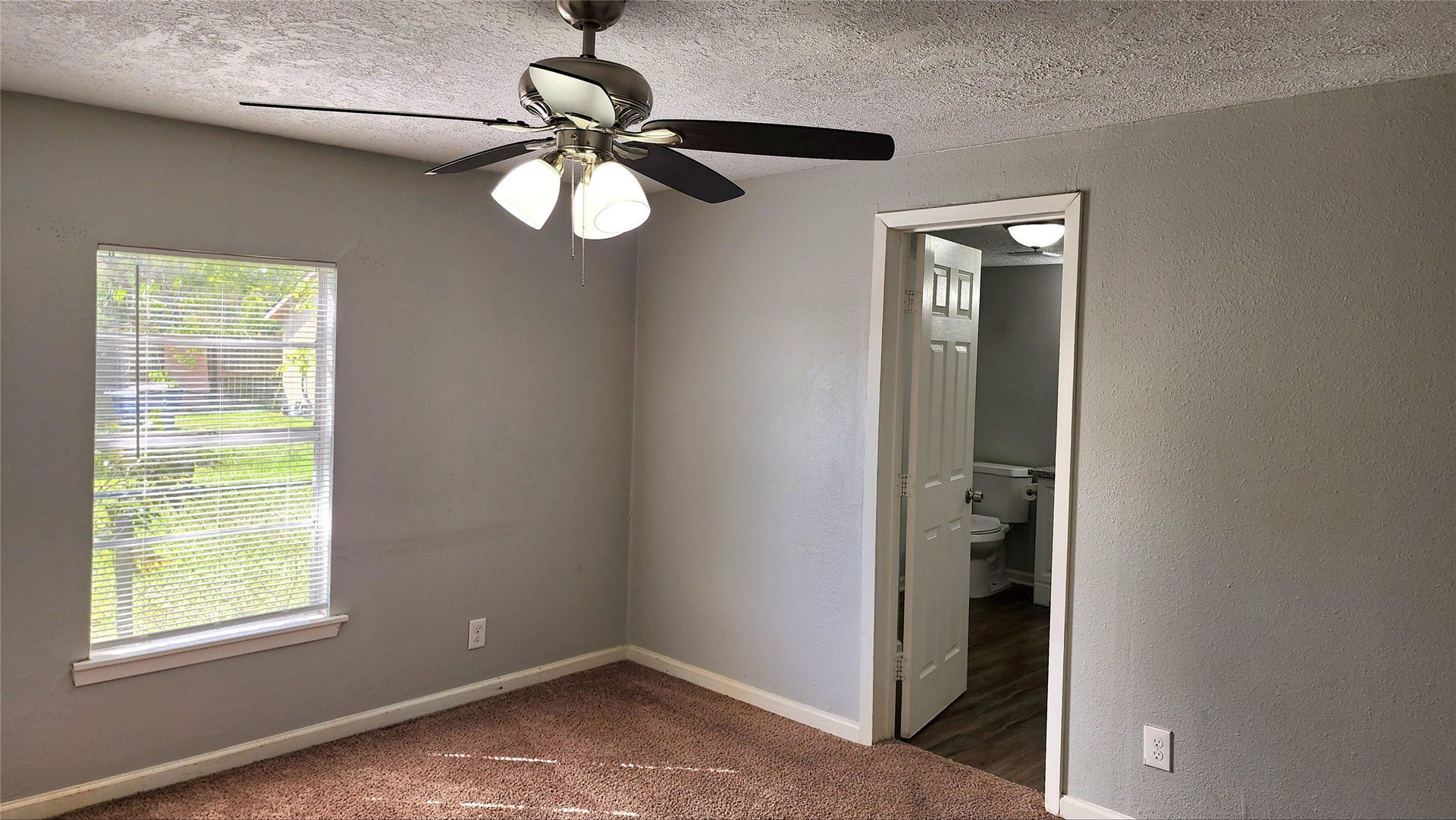 419 N Parrish Street, Angleton, TX 77515 Primary suite with a ceiling fan, window, and direct access to its private ensuite bath.