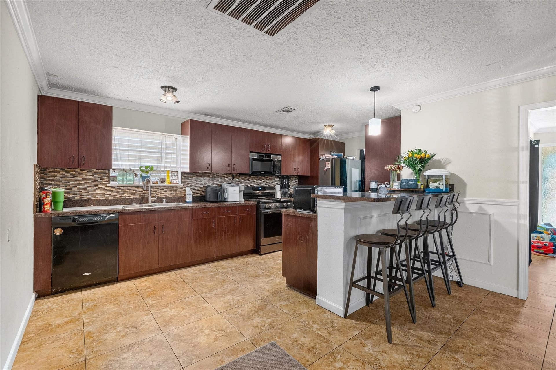 The kitchen impresses with beautiful stone countertops, a stylish backsplash, and a spacious peninsula island that provides additional prep space and a perfect spot for casual dining or entertaining.