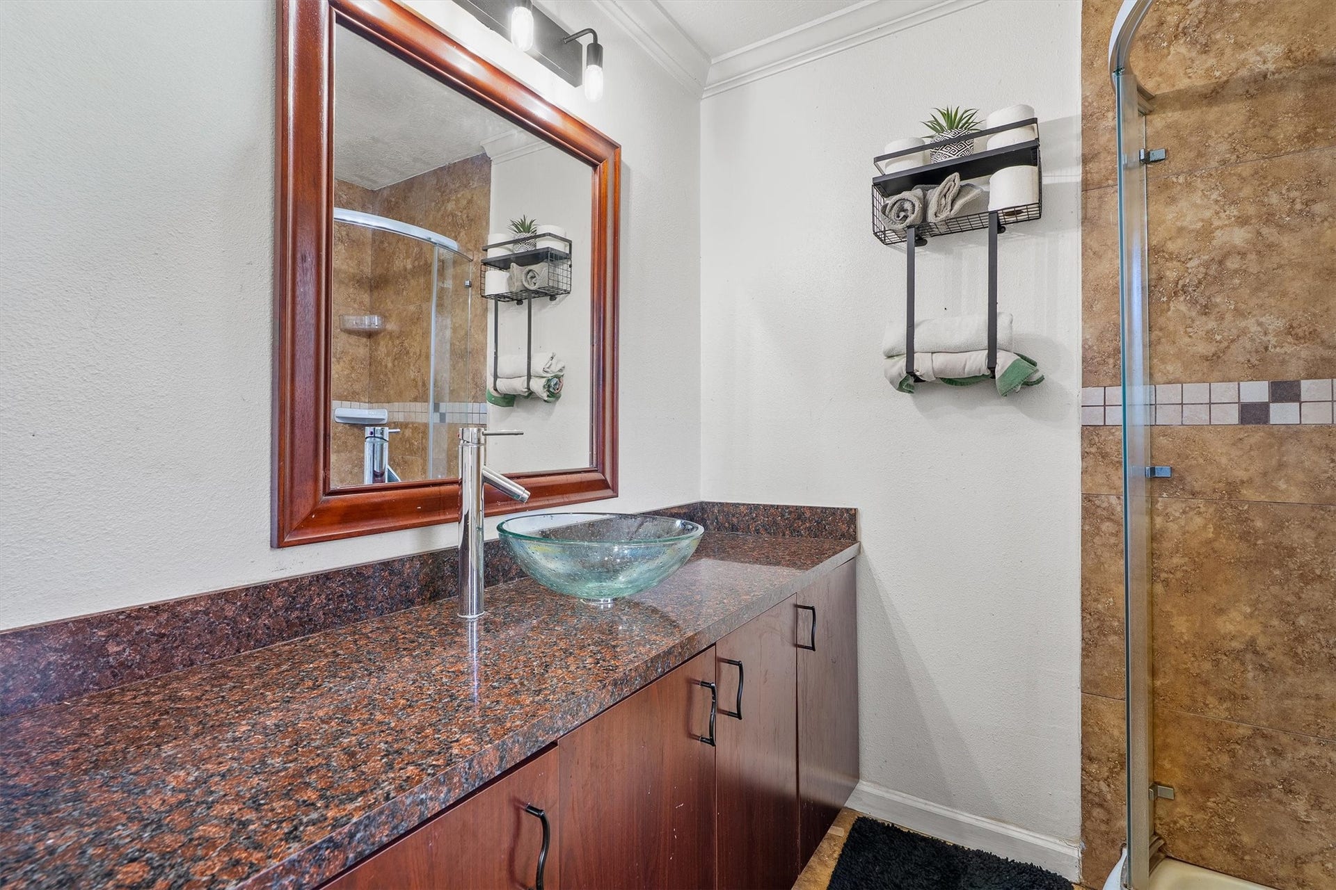 The primary bathroom boasts a generously sized vanity topped with a stylish vessel sink, creating an elegant focal point while offering ample space for your daily essentials.