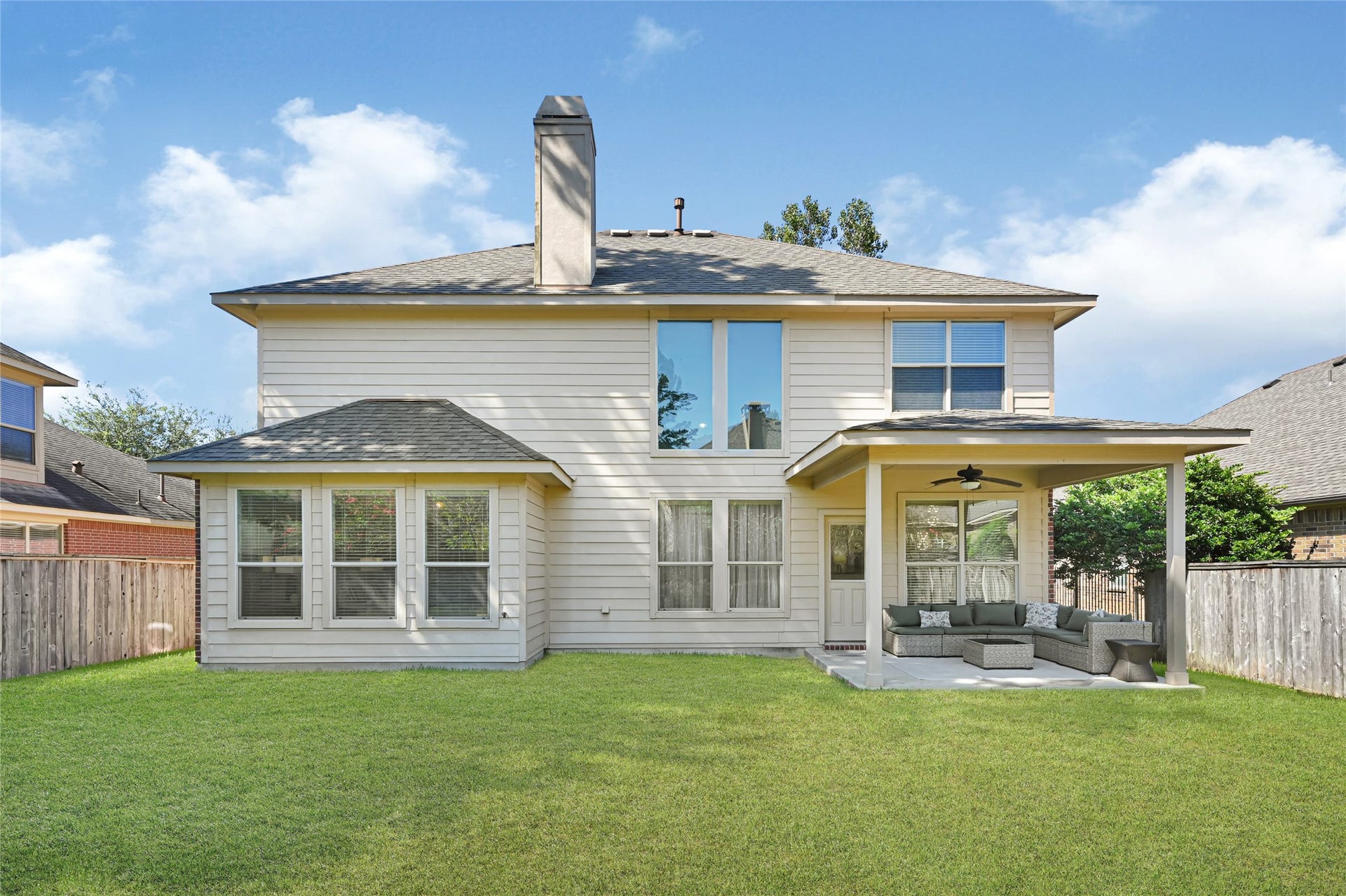 Charming two-story home with a spacious backyard, featuring a covered patio perfect for outdoor relaxation and entertaining.