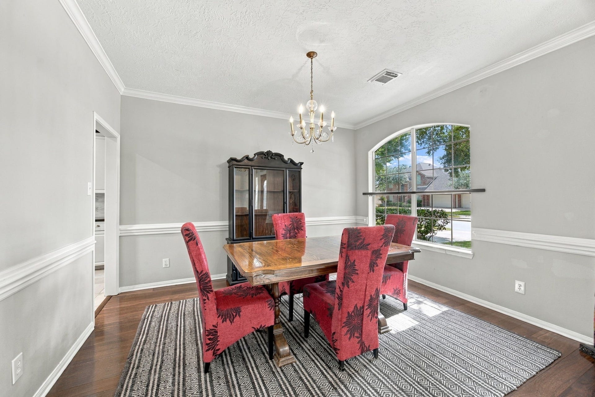 2417 La Rochelle Court, Seabrook, TX 77586 Elegant dining room featuring a large window that fills the space with natural light, complemented by a classic chandelier and rich wood flooring.