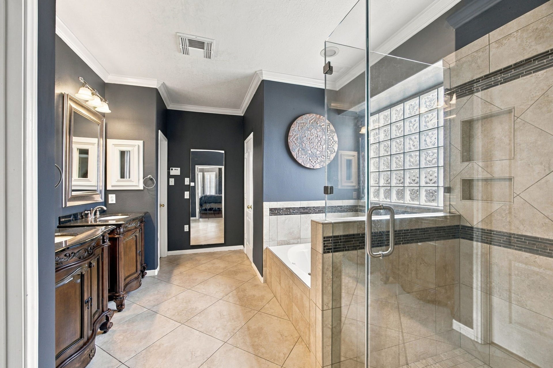 2417 La Rochelle Court, Seabrook, TX 77586 Elegant bathroom featuring a spacious glass-enclosed shower, a luxurious soaking tub, and a dual-sink vanity with rich wood cabinetry.