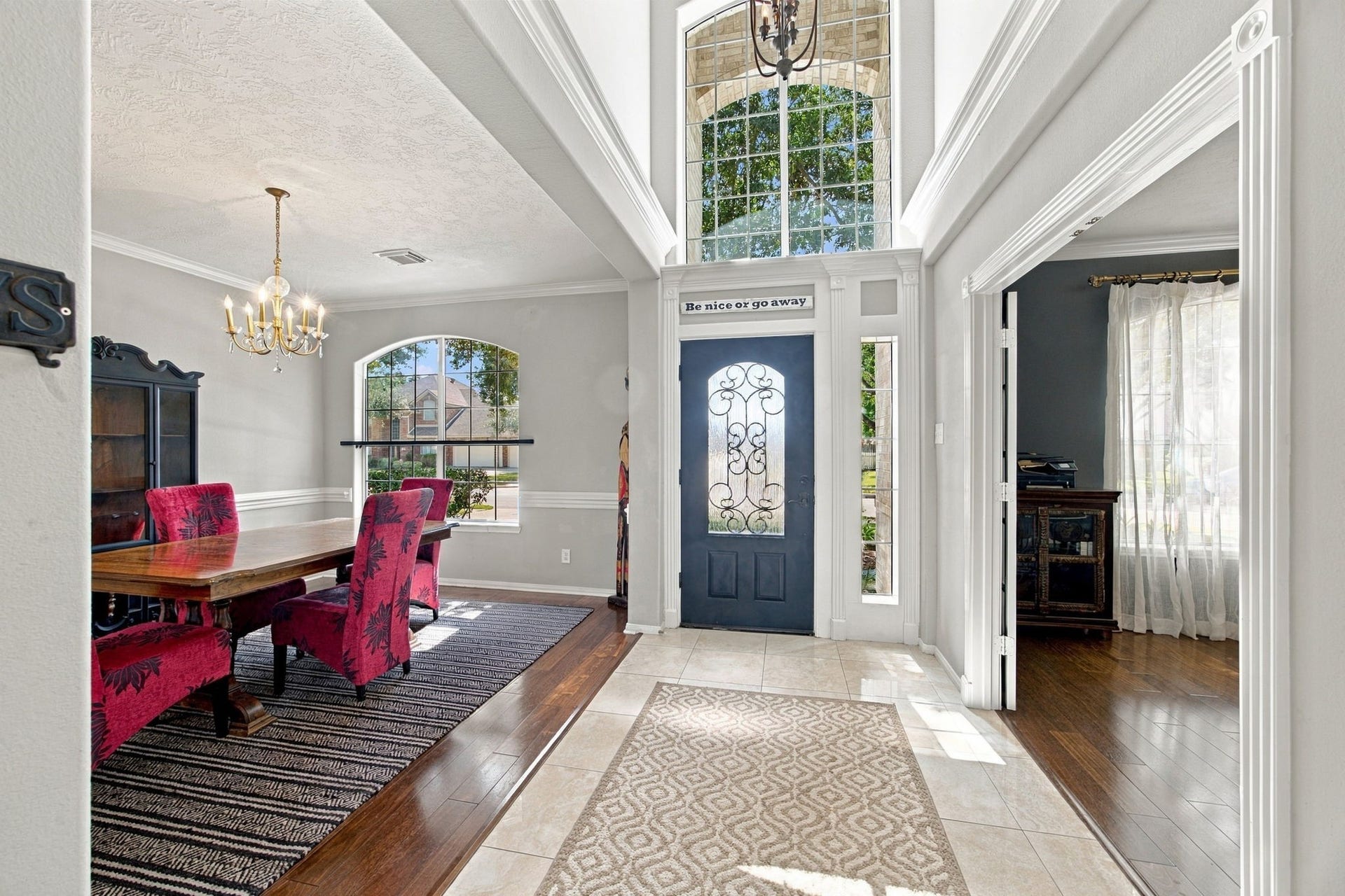 2417 La Rochelle Court, Seabrook, TX 77586 Elegant entryway with high ceilings and abundant natural light, featuring a stylish chandelier and a welcoming view into the dining area with vibrant red chairs.