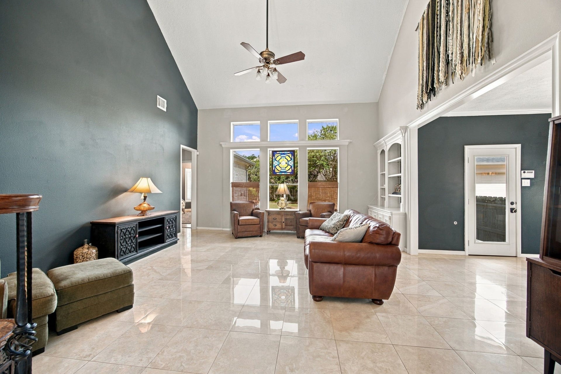 2417 La Rochelle Court, Seabrook, TX 77586 Spacious living room with high ceilings, elegant tile flooring, and abundant natural light from large windows, featuring a cozy seating area perfect for relaxation.