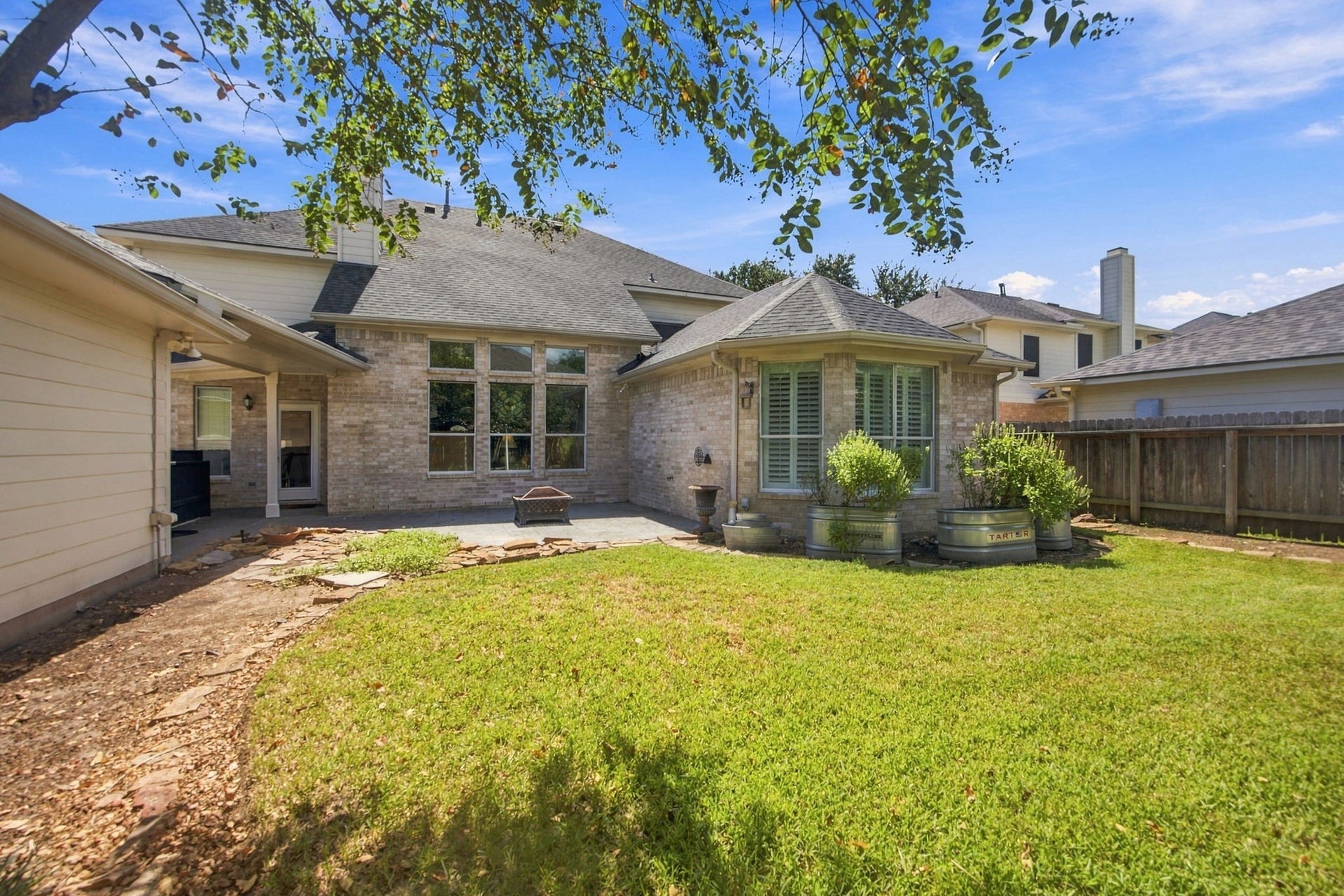 2417 La Rochelle Court, Seabrook, TX 77586 Charming backyard featuring a spacious patio, manicured lawn, and elegant brick exterior, perfect for outdoor relaxation and entertaining.
