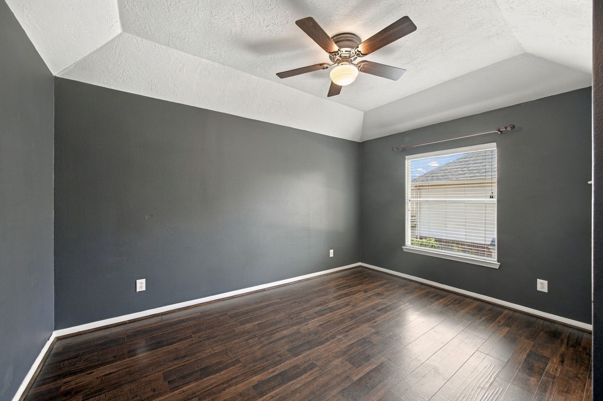 2417 La Rochelle Court, Seabrook, TX 77586 Spacious room with rich dark wood flooring, a stylish ceiling fan, and ample natural light from a large window, perfect for a cozy retreat.
