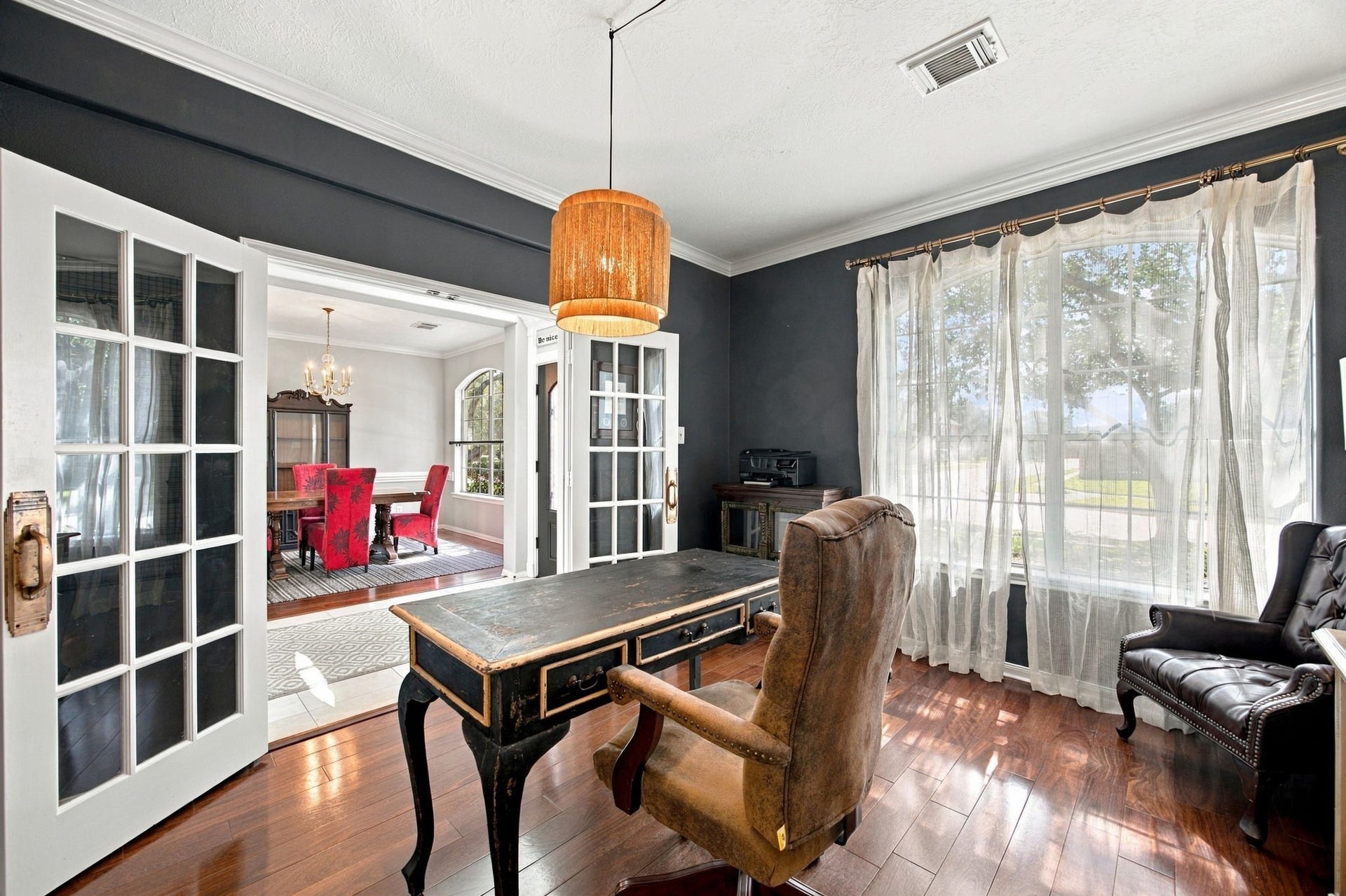 2417 La Rochelle Court, Seabrook, TX 77586 Elegant home office with rich wood flooring, large window for natural light, and classic French doors leading to a stylish dining area.