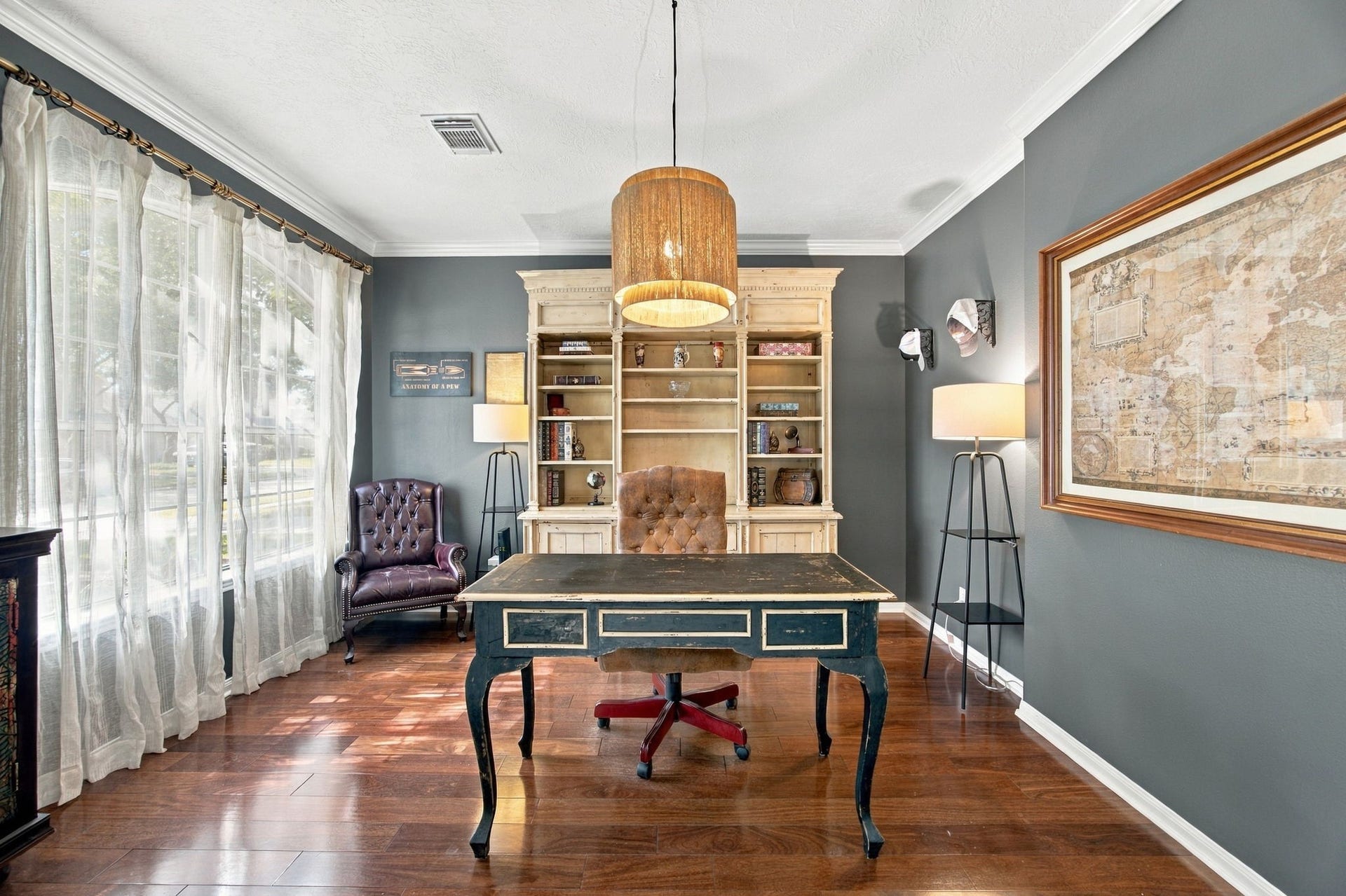 2417 La Rochelle Court, Seabrook, TX 77586 Elegant home office featuring rich hardwood floors, abundant natural light from large windows, and sophisticated furnishings, creating an inviting workspace.