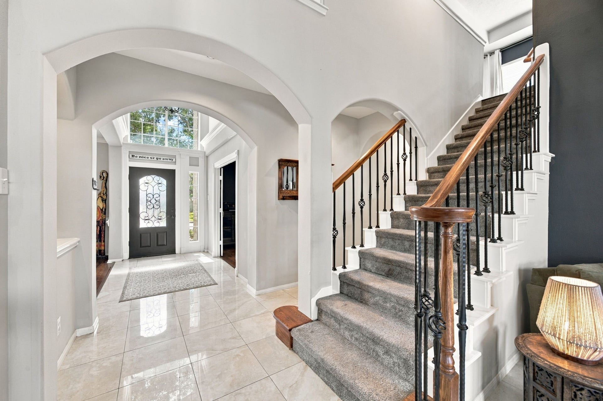 2417 La Rochelle Court, Seabrook, TX 77586 Elegant entryway featuring a grand staircase with wrought iron railings, gleaming tile floors, and abundant natural light through tall windows.