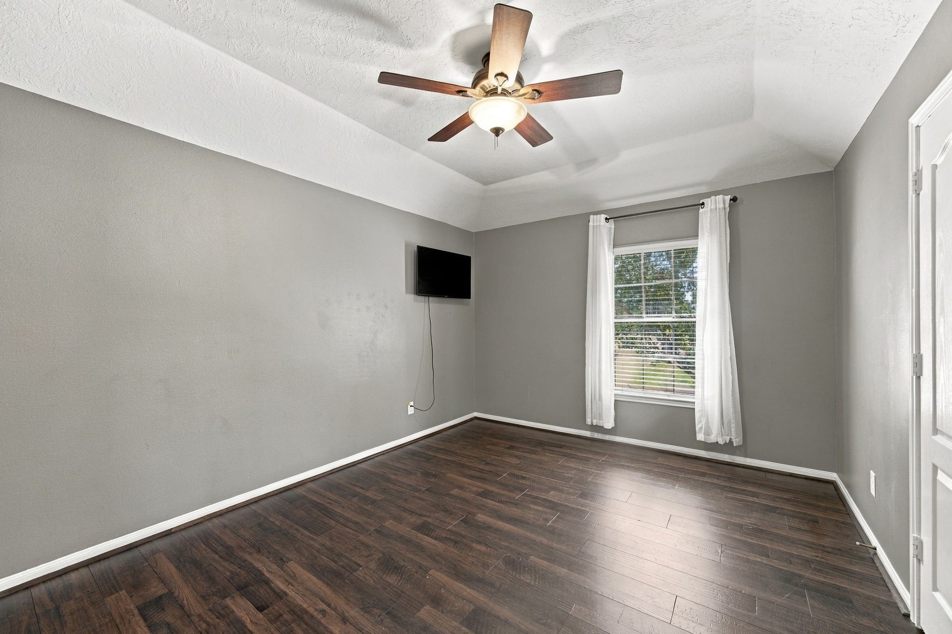 2417 La Rochelle Court, Seabrook, TX 77586 Spacious room with sleek hardwood floors, a large window for natural light, and a ceiling fan for added comfort.