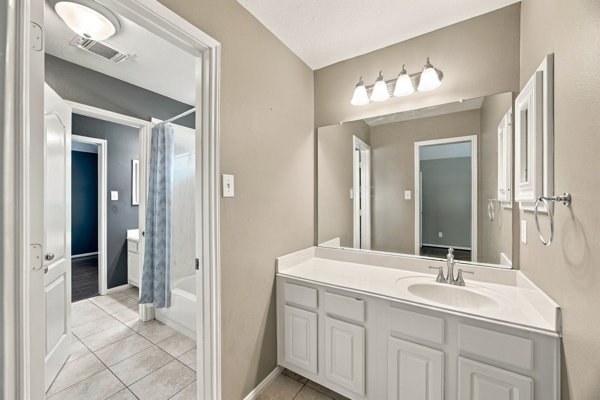 2417 La Rochelle Court, Seabrook, TX 77586 Bright bathroom featuring a large mirror, modern lighting, and a sleek vanity with ample storage, leading to a shower-tub combo for convenience.