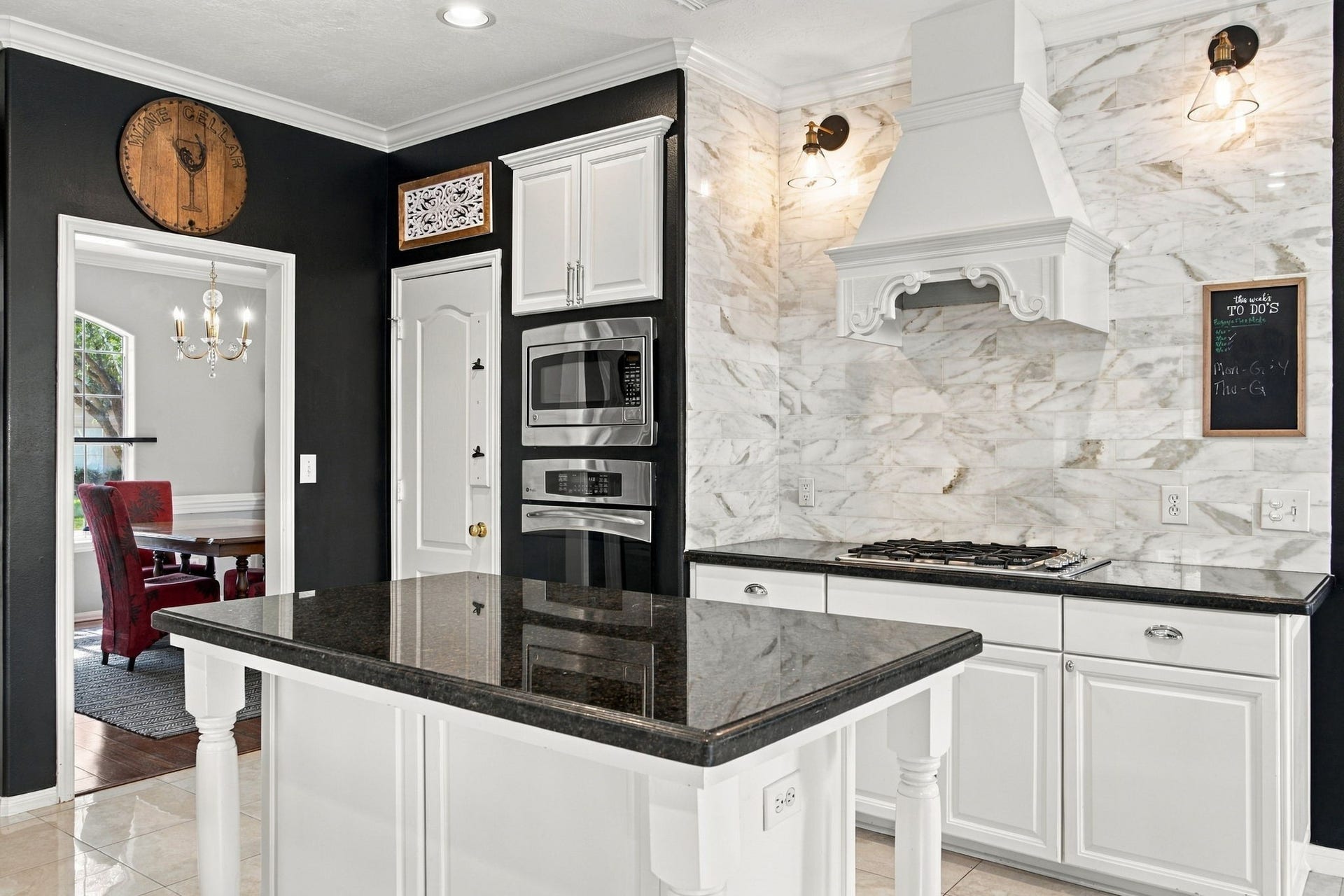 2417 La Rochelle Court, Seabrook, TX 77586 Elegant kitchen featuring a sleek black and white design, with a spacious island, marble backsplash, and built-in stainless steel appliances.