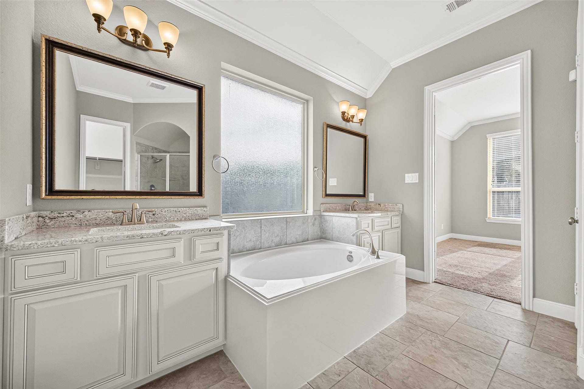 Spacious primary en-suite bath with a soaking tub, glass-enclosed shower, double vanities, and large walk-in closet.