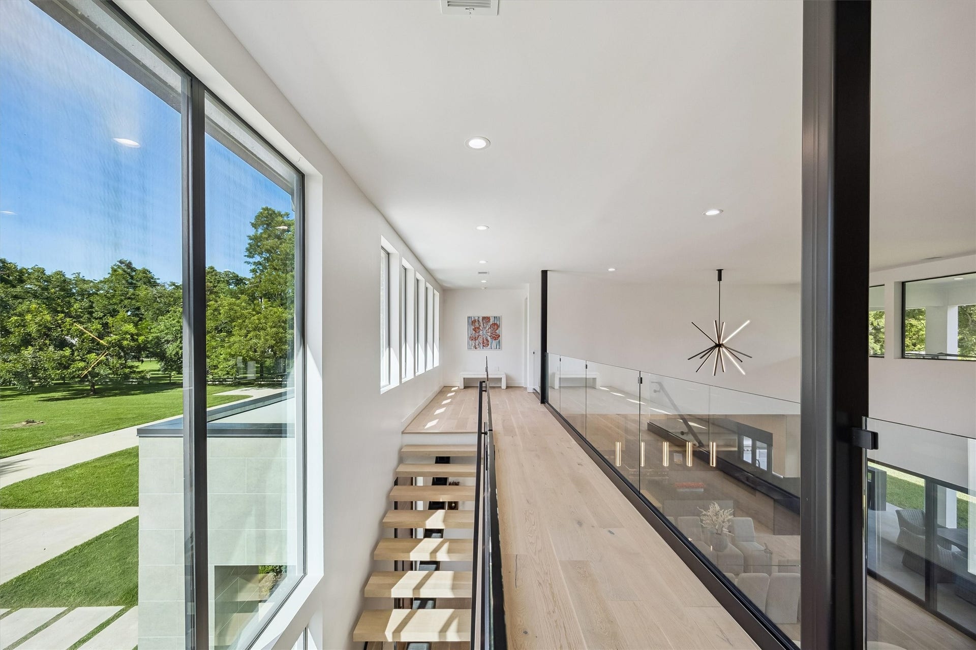 5210 Manor Drive, Sugar Land, TX 77479 Experience modern elegance with this bright, open hallway featuring floor-to-ceiling windows, sleek wood flooring, and a striking contemporary chandelier, offering scenic views and abundant natural light.
