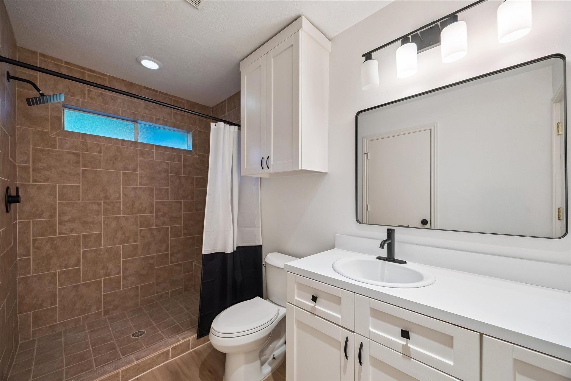 5210 Manor Drive, Sugar Land, TX 77479 Elegant bathroom featuring a spacious walk-in shower with modern tilework, sleek vanity with ample storage, and stylish lighting.