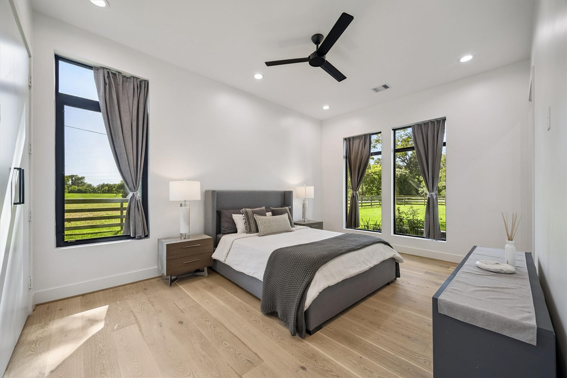 5210 Manor Drive, Sugar Land, TX 77479 Bright and spacious bedroom featuring large windows with scenic views, sleek modern furnishings, and elegant hardwood flooring.