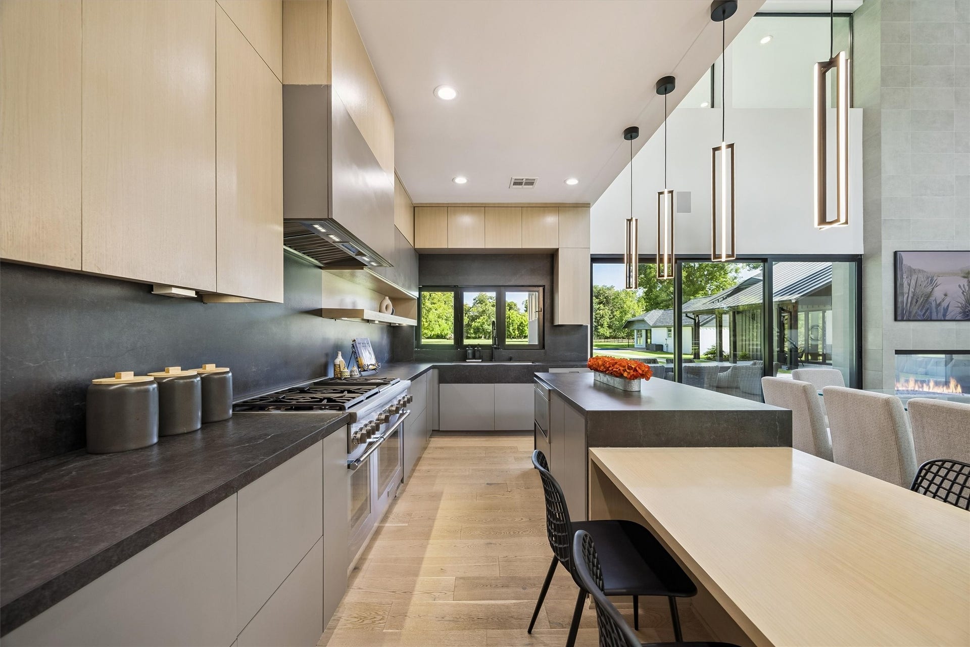 5210 Manor Drive, Sugar Land, TX 77479 Sleek modern kitchen with high-end appliances, spacious countertops, and elegant pendant lighting, seamlessly connected to a bright dining area with large windows offering scenic views.