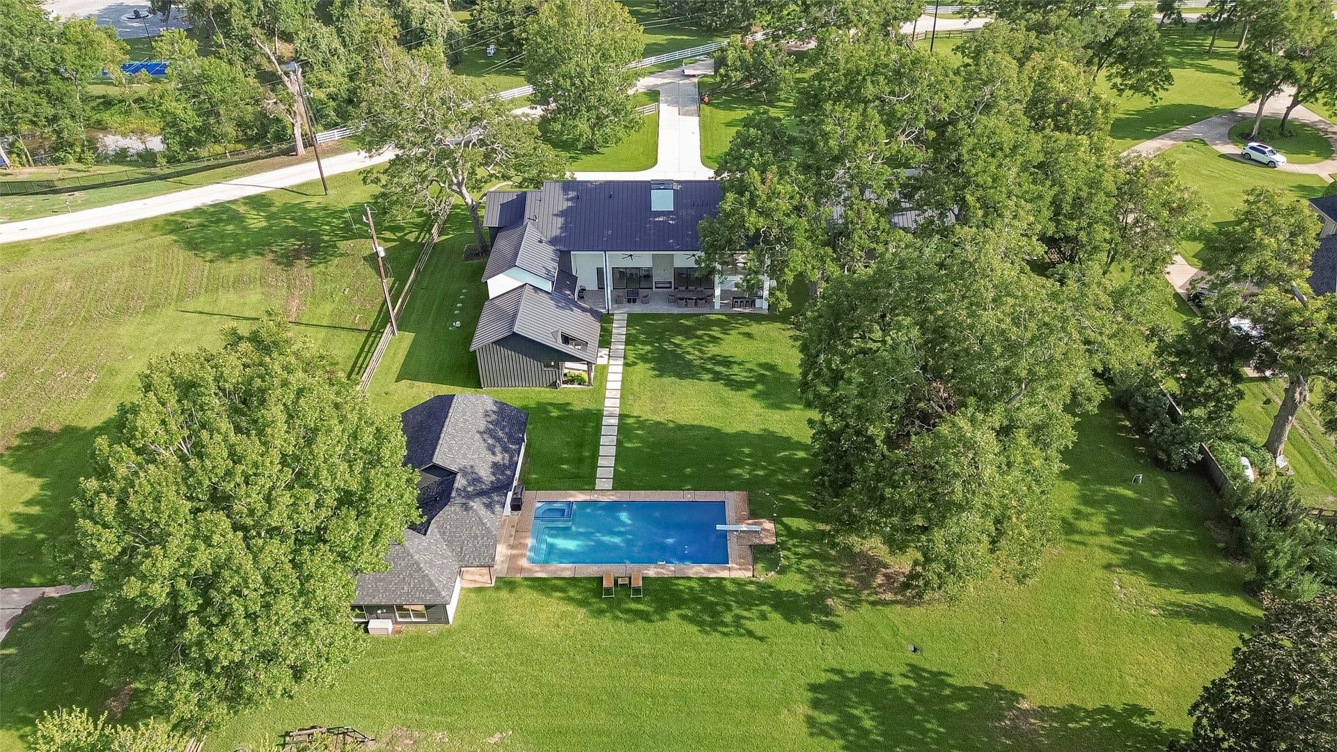 5210 Manor Drive, Sugar Land, TX 77479 Expansive property featuring a modern home with a sleek design, surrounded by lush greenery and a pristine pool, offering a serene and private retreat.