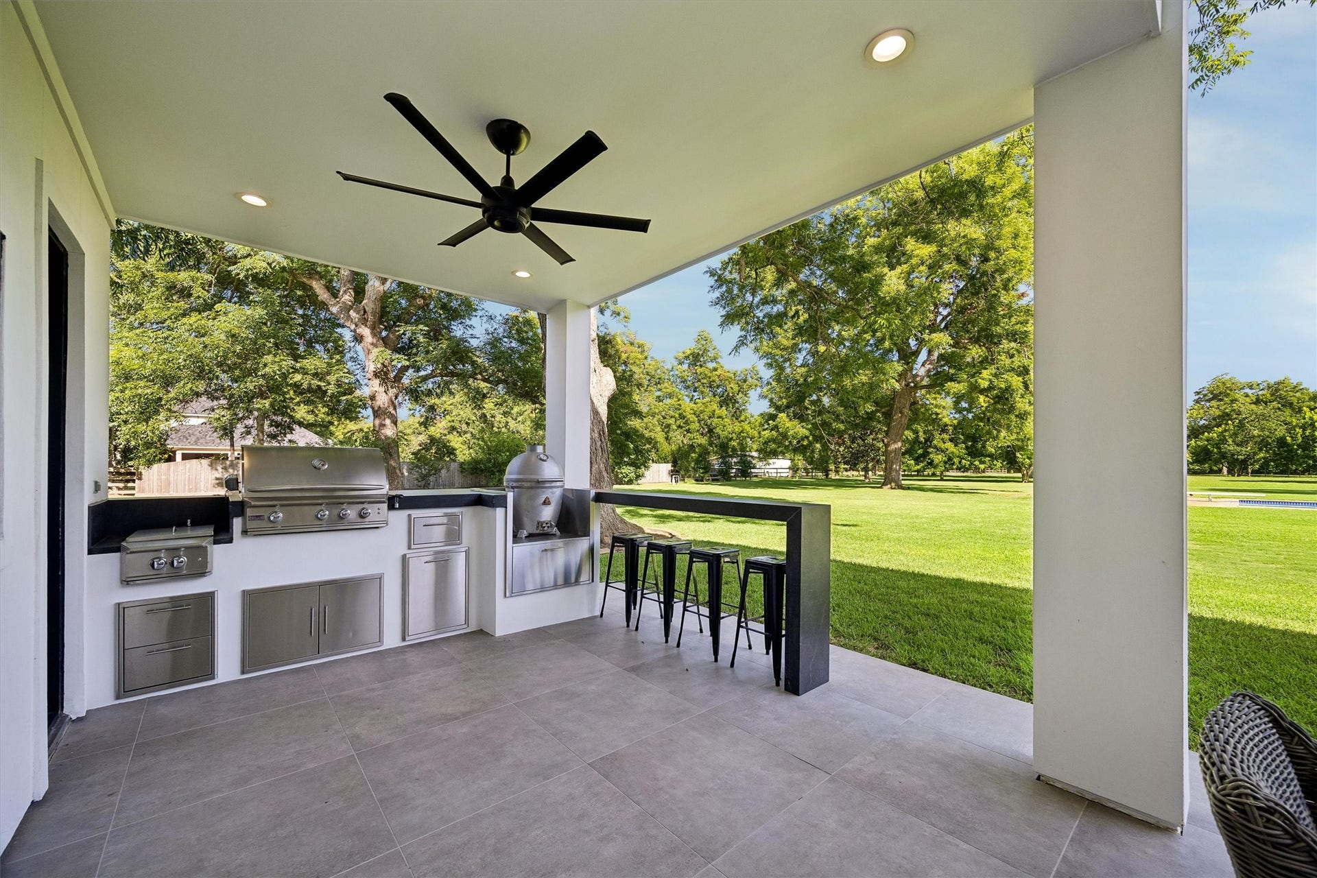 5210 Manor Drive, Sugar Land, TX 77479 Experience outdoor luxury with a stylish covered patio featuring a state-of-the-art built-in grill, spacious counter space, and ample seating, all overlooking a lush green landscape.