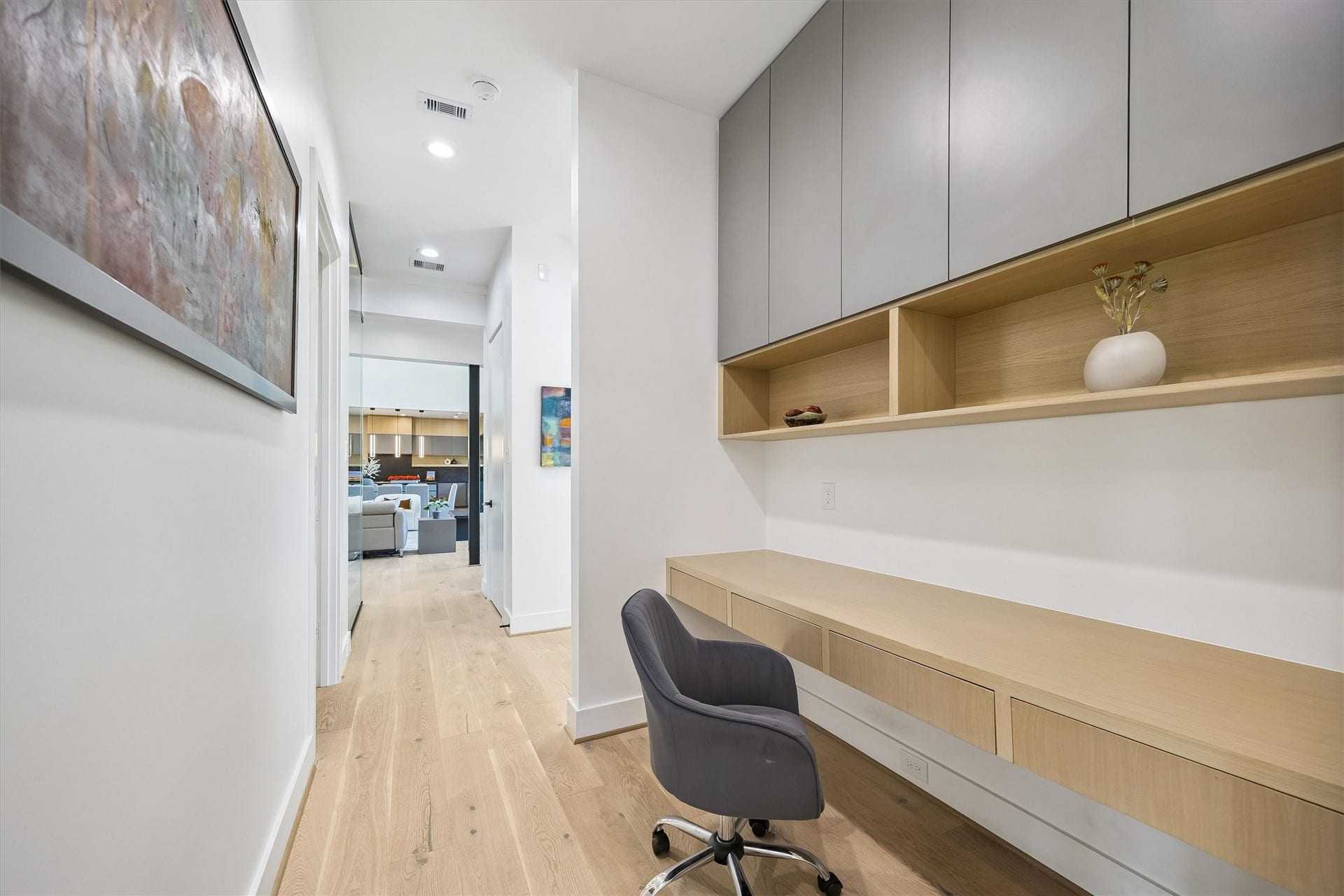 5210 Manor Drive, Sugar Land, TX 77479 Sleek and modern hallway workspace with ample storage, featuring built-in cabinetry and a stylish desk area, leading into a cozy living space.