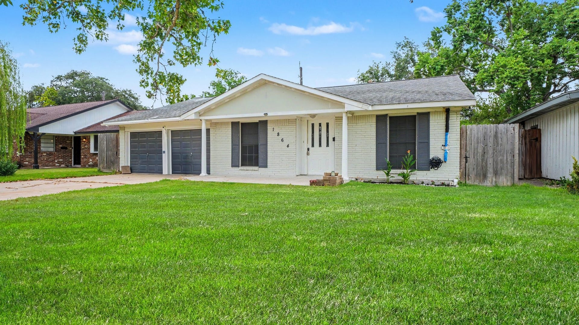 Charming single-story home with a classic brick exterior, featuring a spacious front lawn and double garage, nestled in a serene neighborhood.