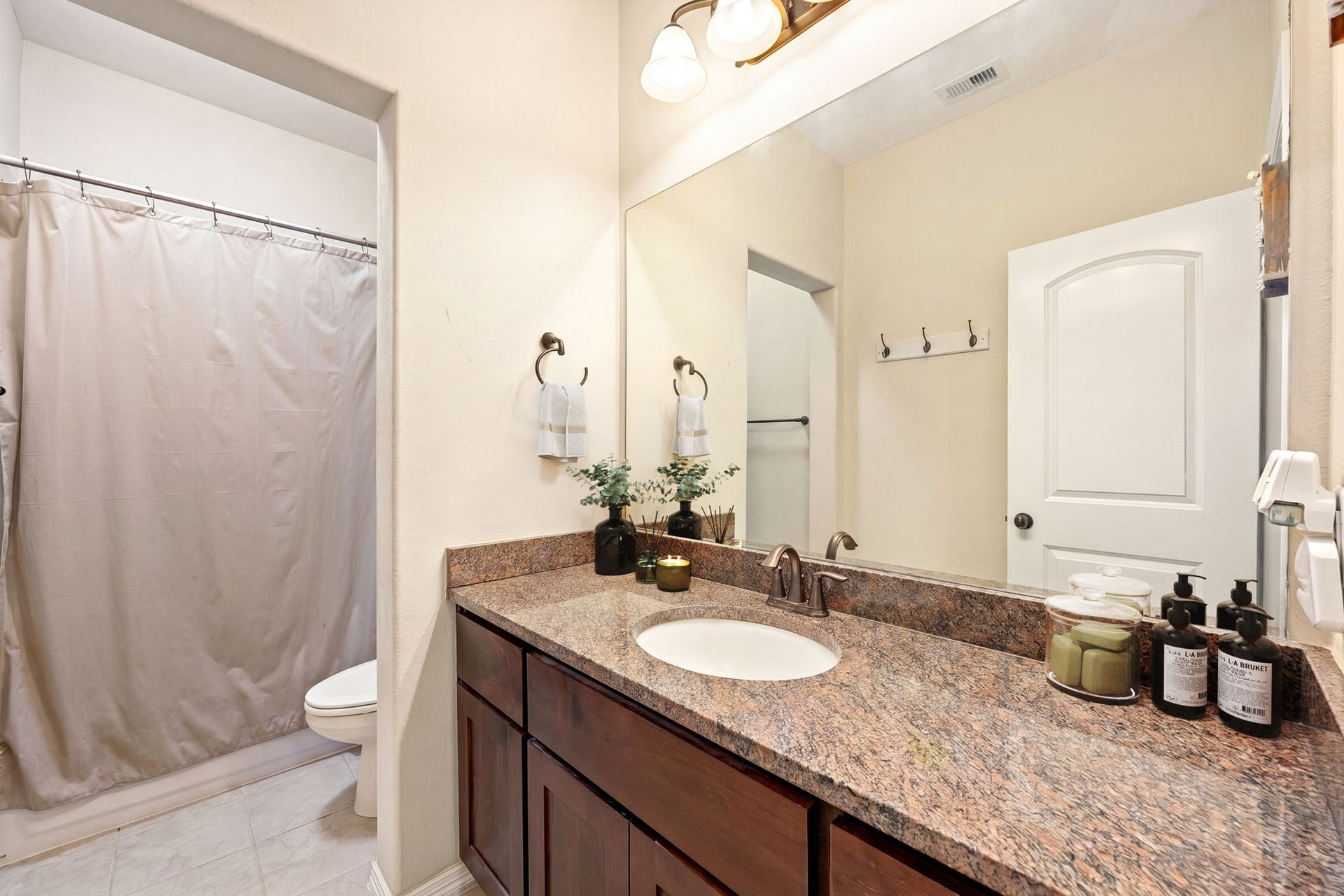 5102 Hawthorne Bend Drive, Katy, TX 77494 Secondary bath with granite countertops, dark wood cabinetry, a large vanity mirror, tub/shower combo, and tile flooring, clean, functional, and ready for move-in!