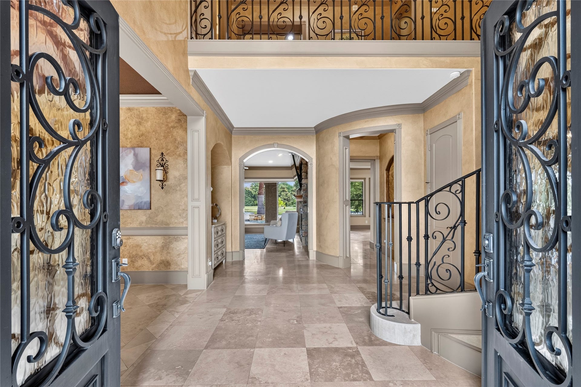 The mediterainian design continues inside the home with soaring ceilings in the foyer, terrazzo tile and a black wrought iron sweeping staircase.