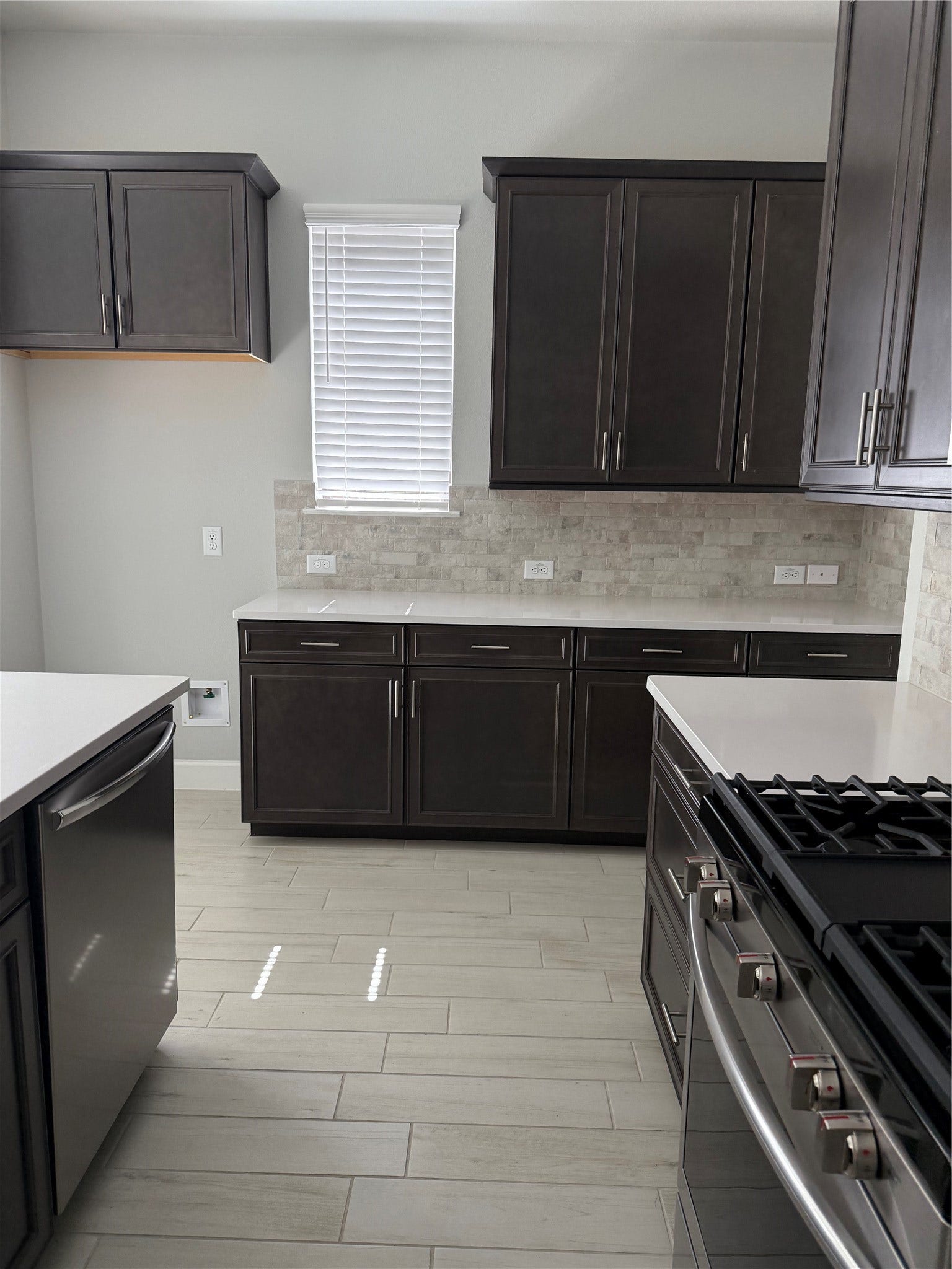10526 William Park Drive, Missouri City, TX 77459 Sleek kitchen featuring elegant dark cabinetry, modern stainless steel appliances, and a bright, neutral backsplash for a contemporary feel.