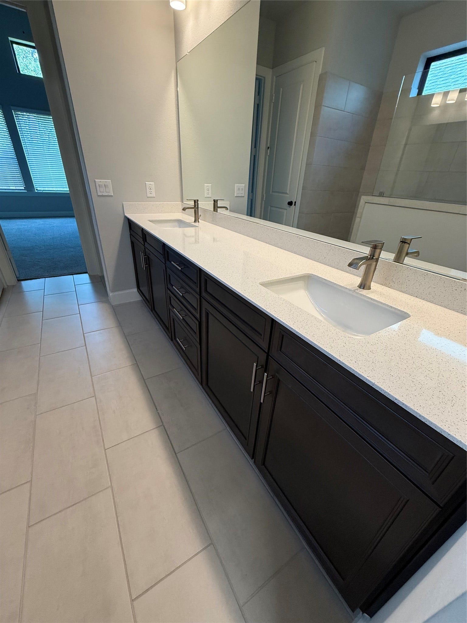 10526 William Park Drive, Missouri City, TX 77459 Elegant bathroom featuring a sleek double vanity with modern fixtures, ample storage, and a large mirror, all set against a backdrop of stylish tile flooring.