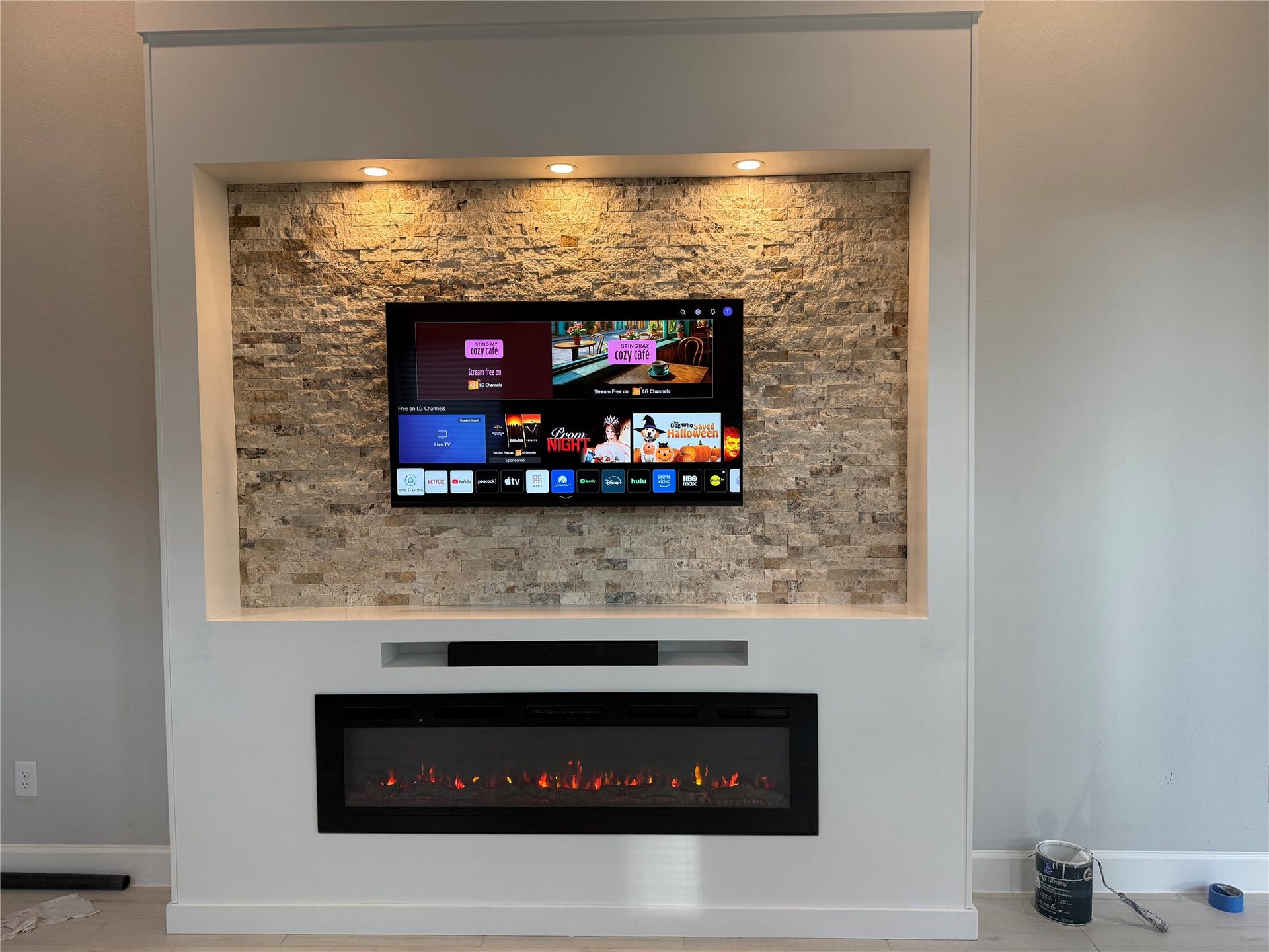 10526 William Park Drive, Missouri City, TX 77459 Modern living space featuring a sleek wall-mounted TV above a stylish electric fireplace set against a textured stone accent wall, enhanced by recessed lighting.