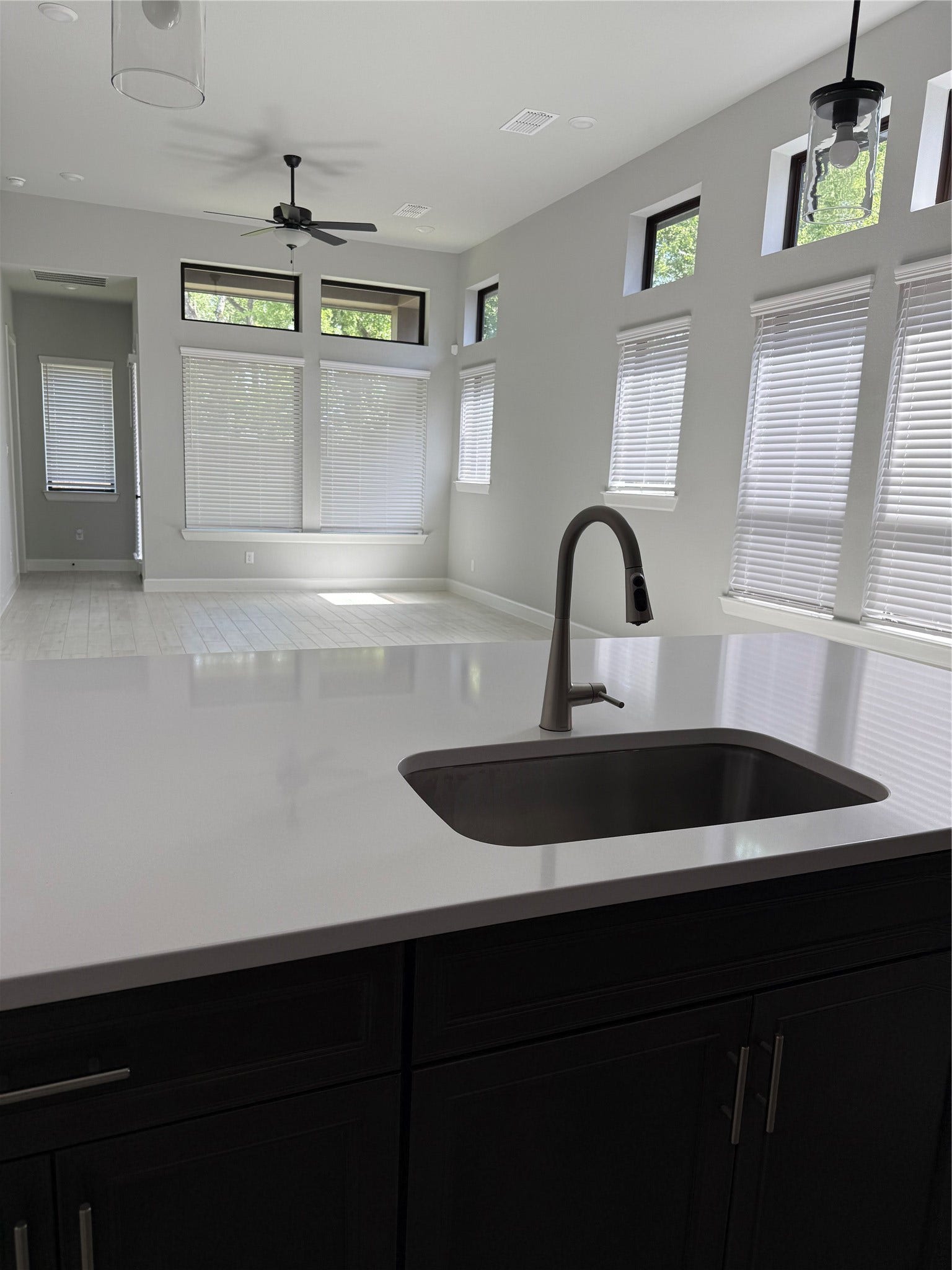 10526 William Park Drive, Missouri City, TX 77459 Bright and airy open-concept space featuring a sleek kitchen island with modern fixtures, ample natural light from large windows, and a ceiling fan for comfort.