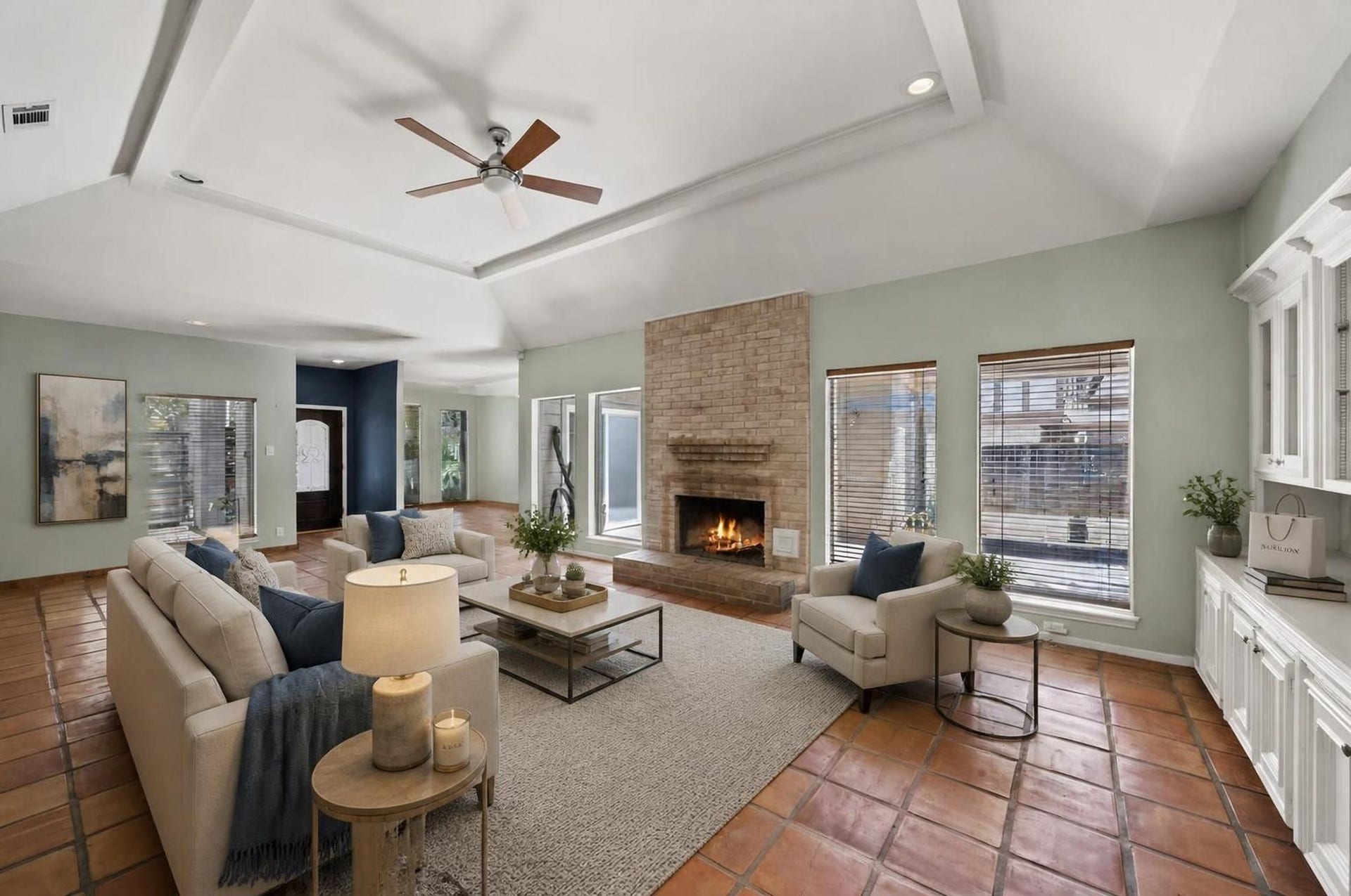 11807 Carriage Hill Drive, Houston, TX 77077 The living room opens into a dramatic main gathering space with vaulted ceilings, tile flooring, a gaslog fireplace, and wide views toward the backyard. The scale of the room creates a strong central point for the home. Virtually staged.