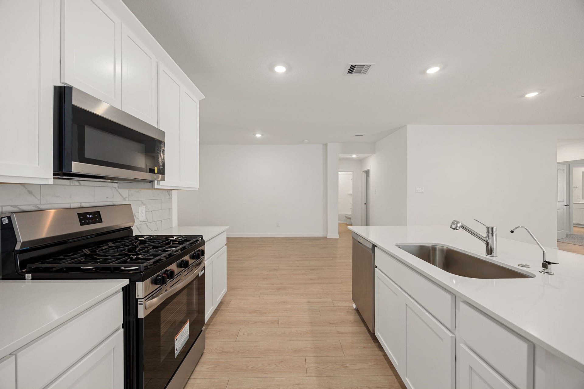 A closer look at the kitchen showcases the gas range, tiled backsplash, and generous counter space, perfect for home-cooked meals.