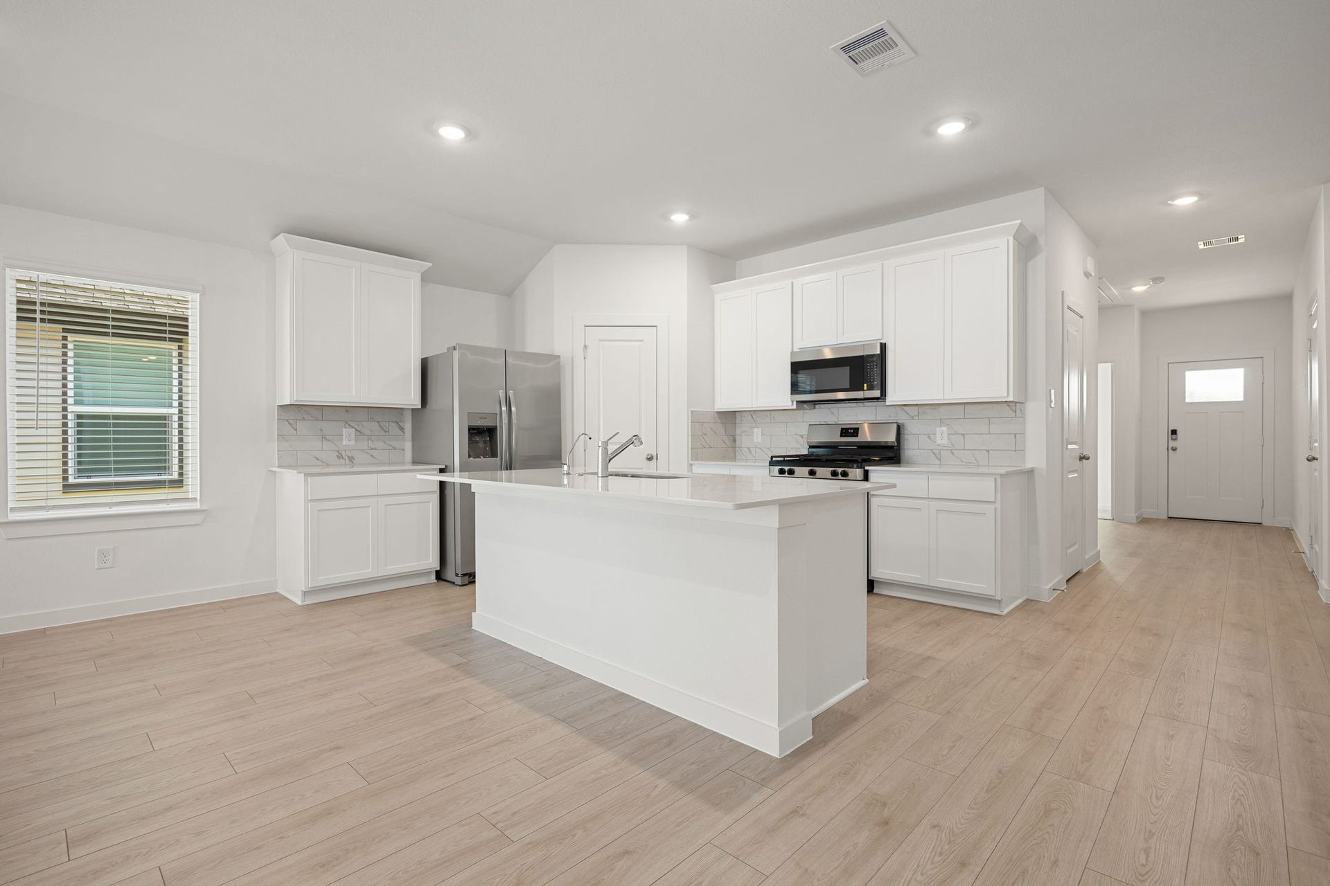 The brand new kitchen offers crisp white cabinetry, a center island with a sink and breakfast bar seating, complemented by sleek granite countertops.