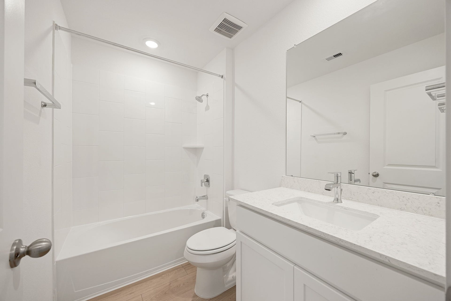 A secondary bathroom features a tub/shower combo and a single-sink vanity with a light-toned countertop.