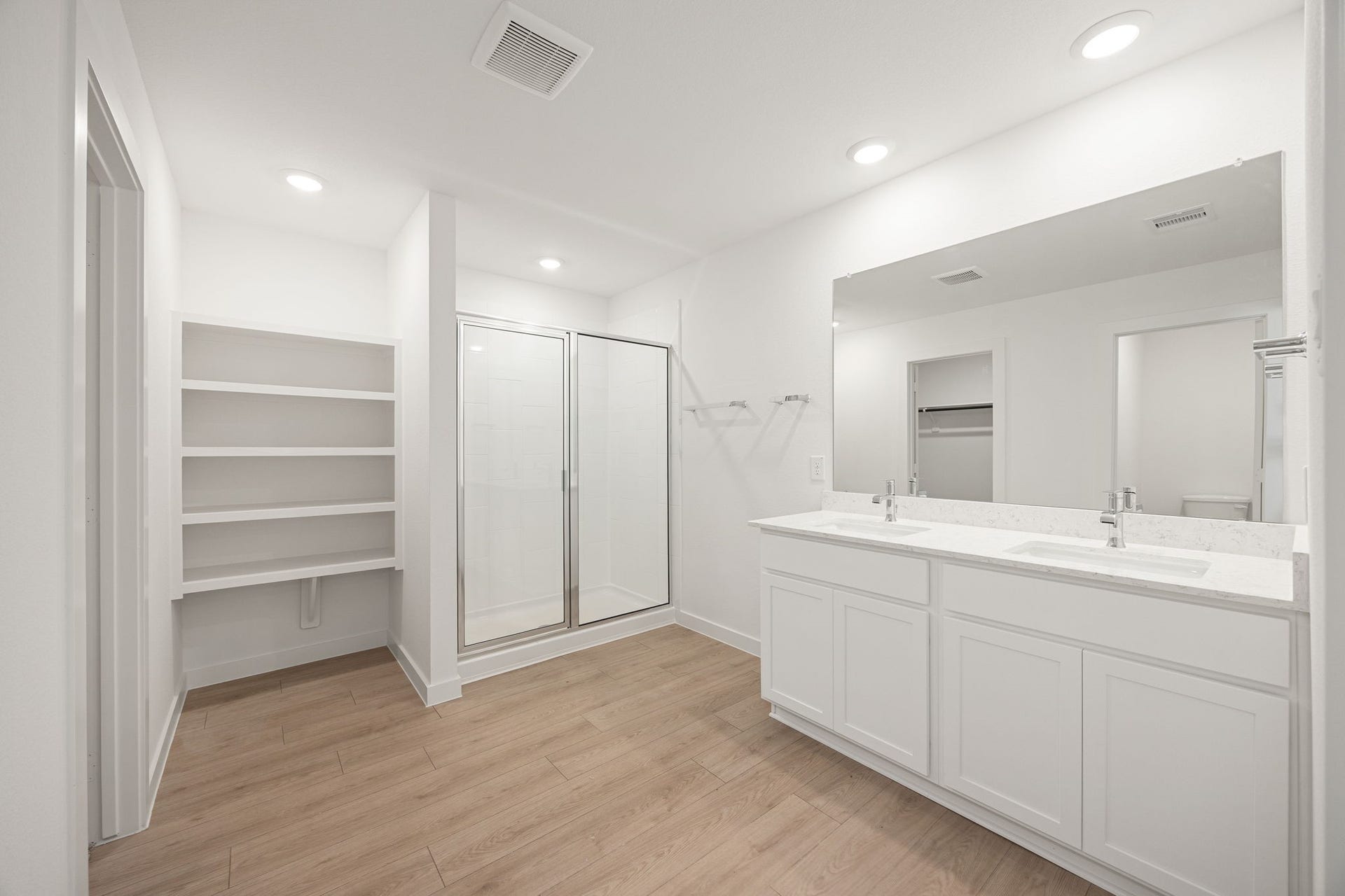 The primary bathroom features a dual-sink vanity with a marble-look countertop, a walk-in shower, and a linen shelving nook for extra storage.