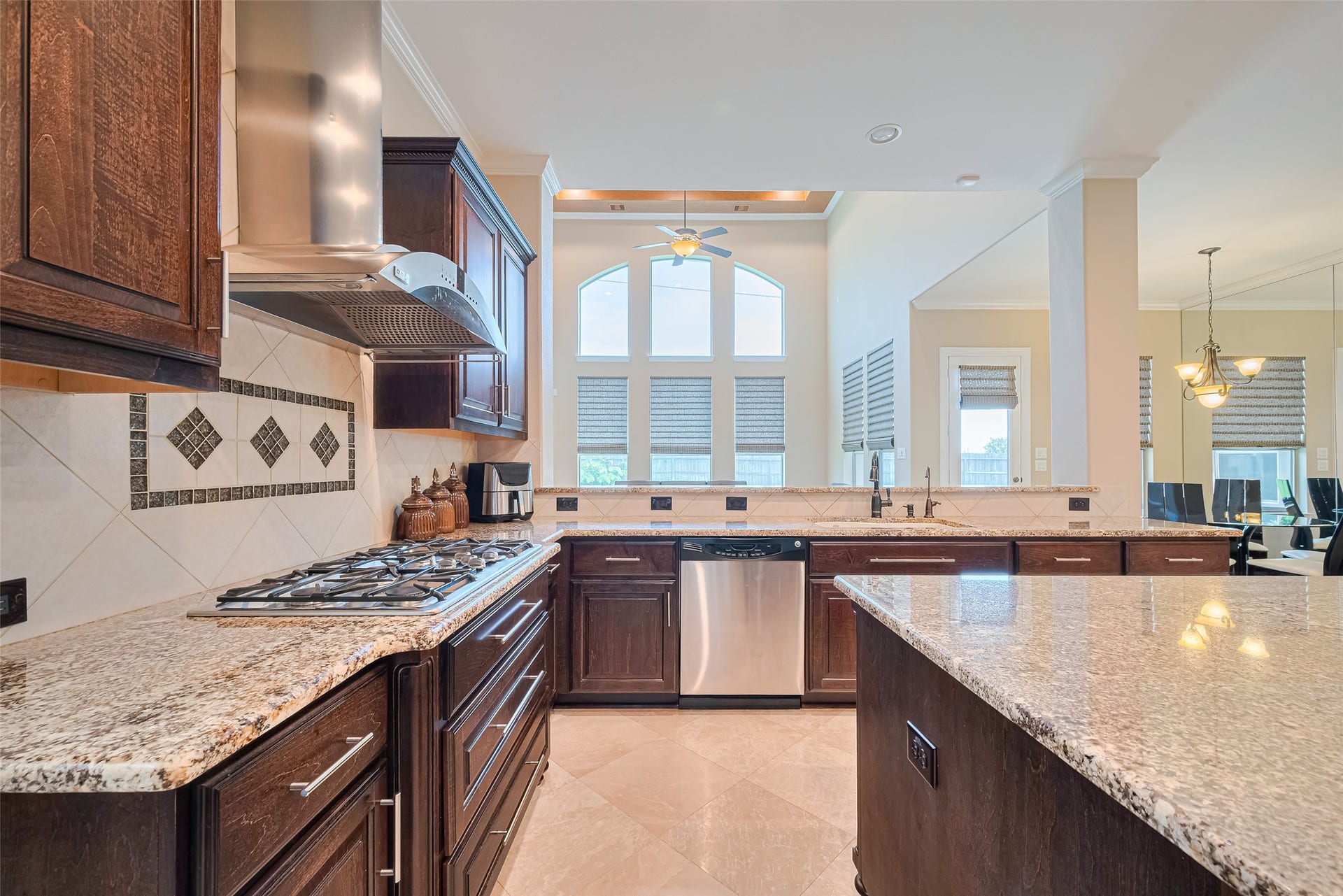 4722 Burclare Court, Sugar Land, TX 77479 Opposite kitchen perspective capturing the decorative tile backsplash, integrated dishwasher, expansive prep surfaces, and clear views toward the breakfast and family areas.