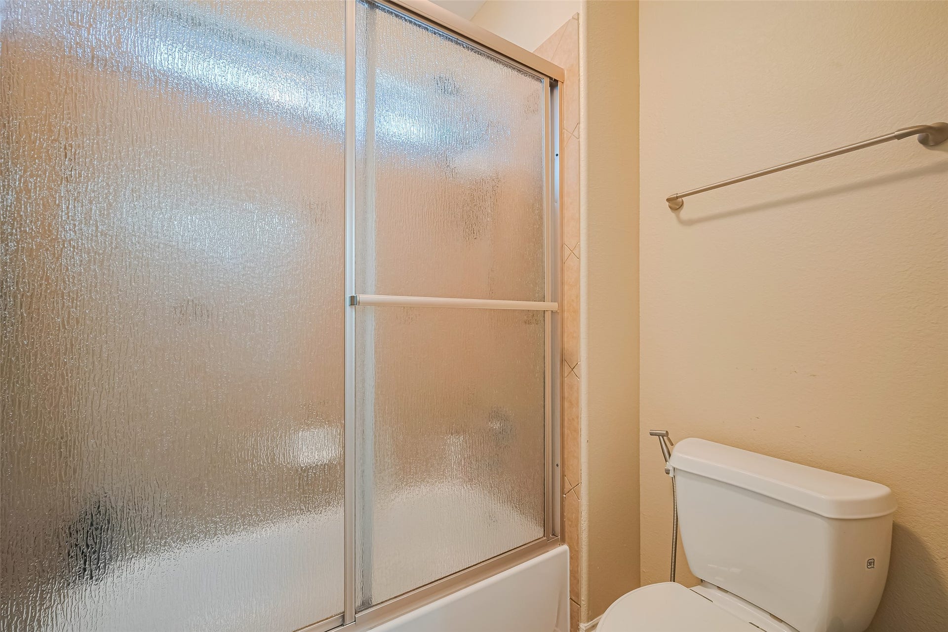 4722 Burclare Court, Sugar Land, TX 77479 Secondary bathroom featuring a tub and shower combination with textured glass enclosure and neutral tile surround.