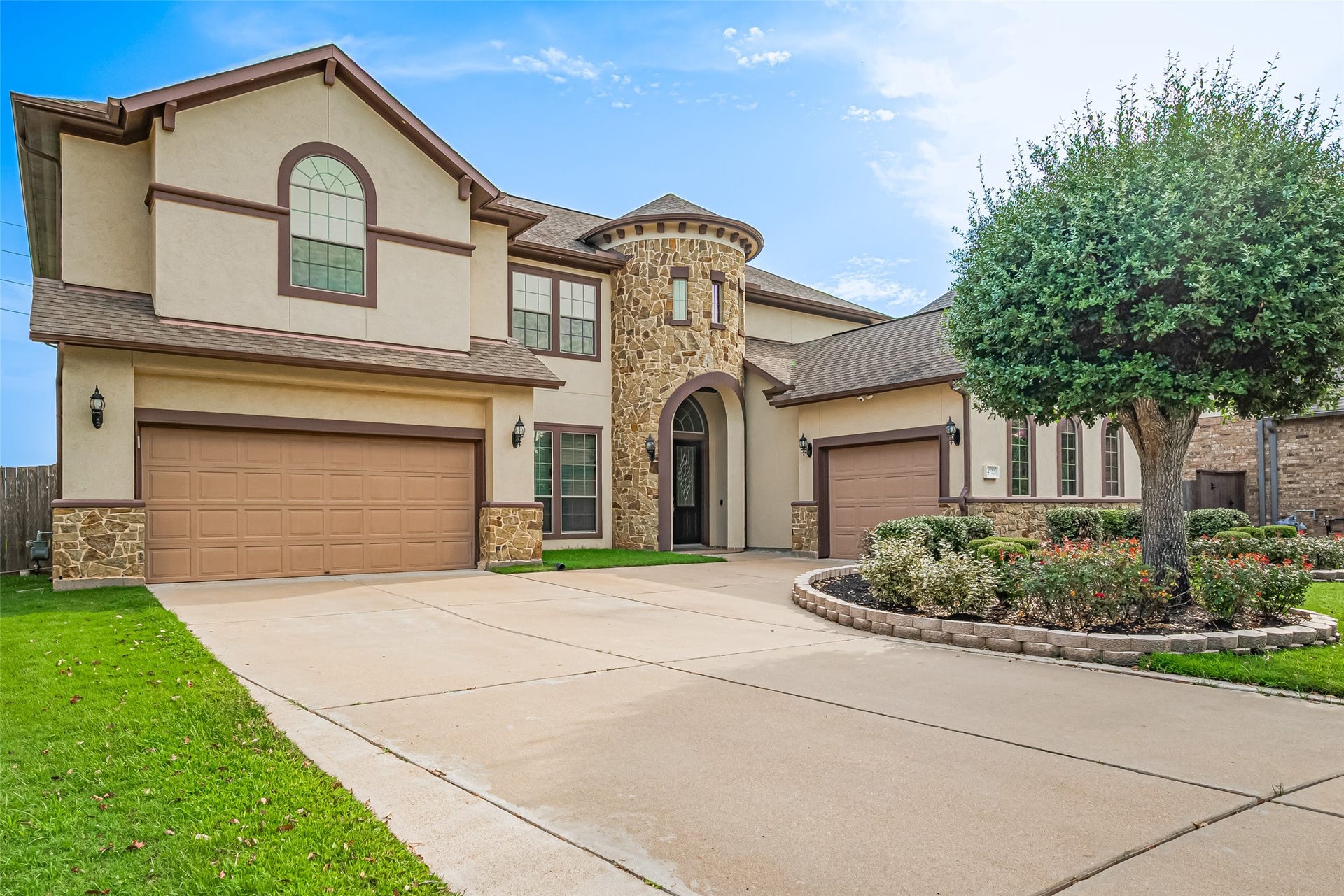 4722 Burclare Court, Sugar Land, TX 77479 Grand driveway view highlighting the three-car garage, dramatic stone turret, and stately arched entryway.