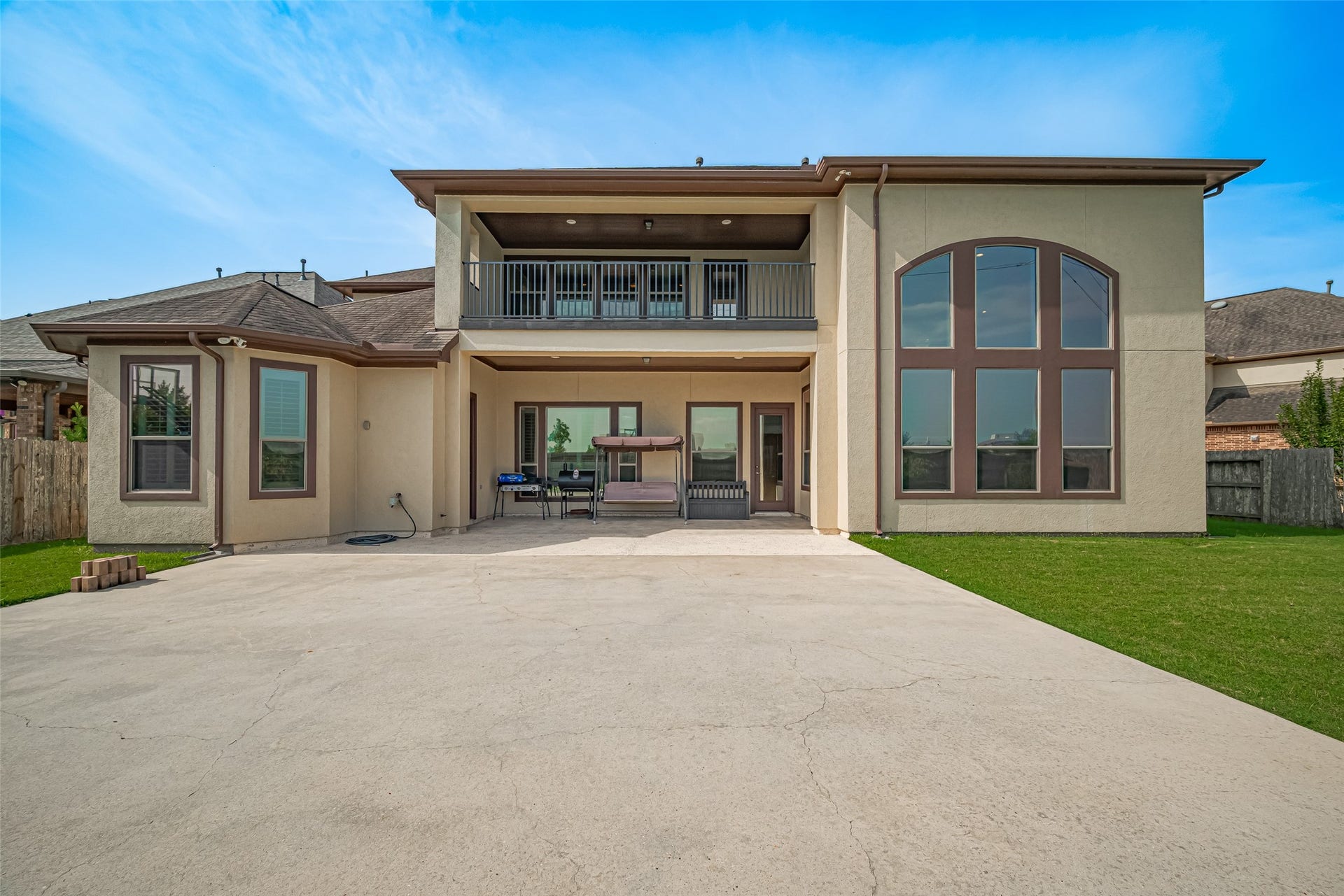 4722 Burclare Court, Sugar Land, TX 77479 Striking rear elevation featuring a spacious covered patio, private upper balcony, expansive windows, and a large concrete recreation area ideal for outdoor entertaining.