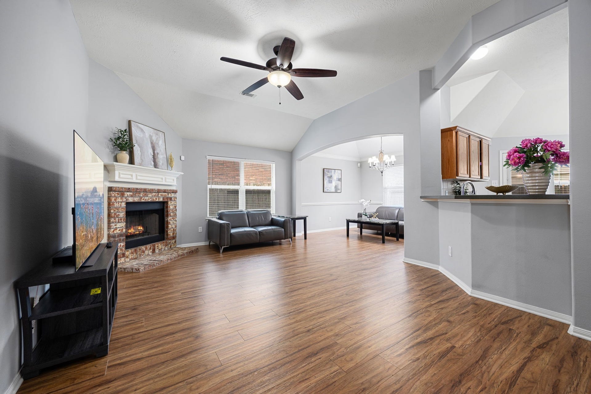 4807 Lake Wichita Lane, Richmond, TX 77407 Living room with a fireplace and wood flooring, opening to the dining area through an arched entry.