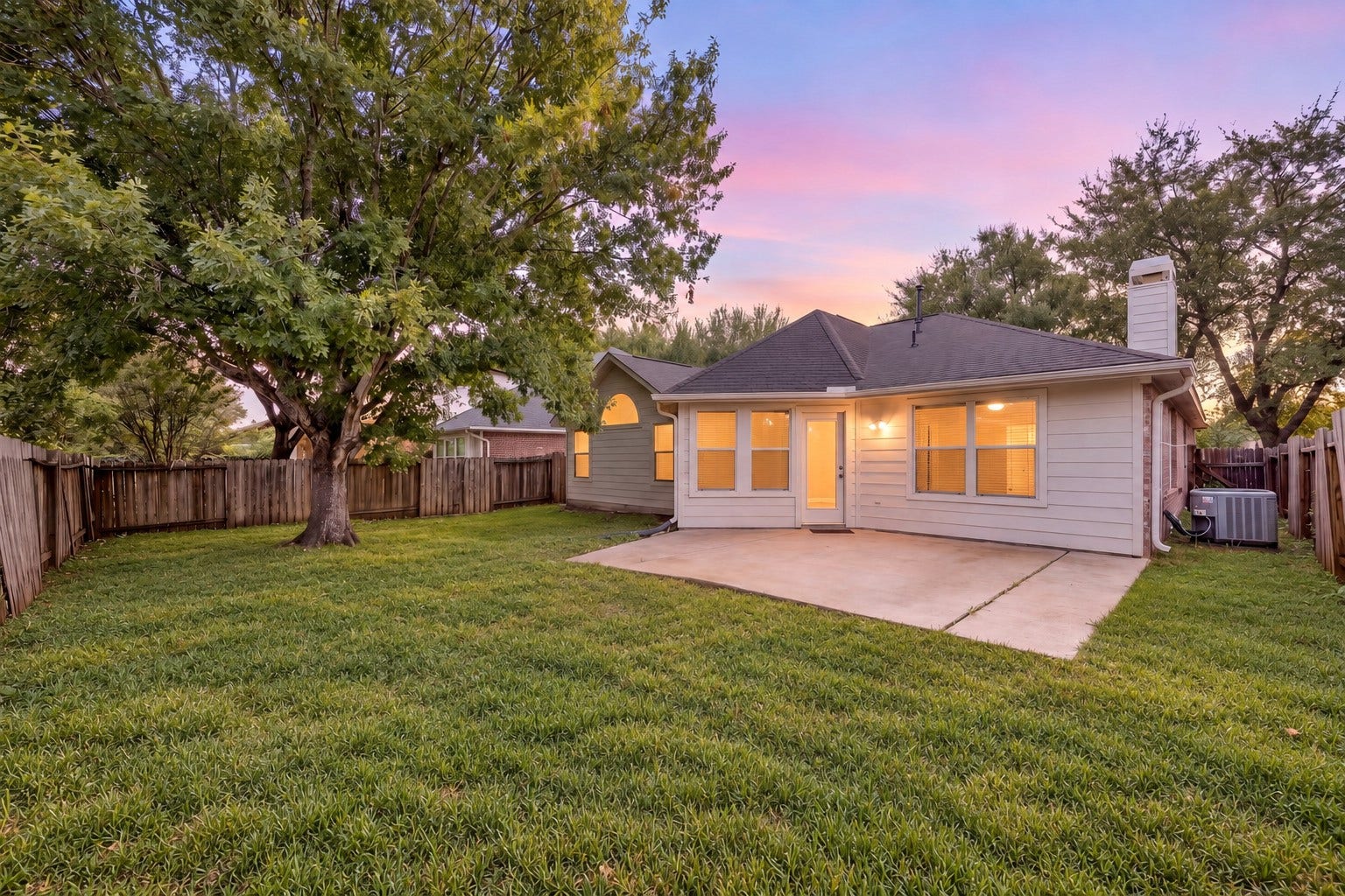 4807 Lake Wichita Lane, Richmond, TX 77407 Backyard with a large concrete patio, full fencing, and mature shade trees, leaving open lawn for seating and play.