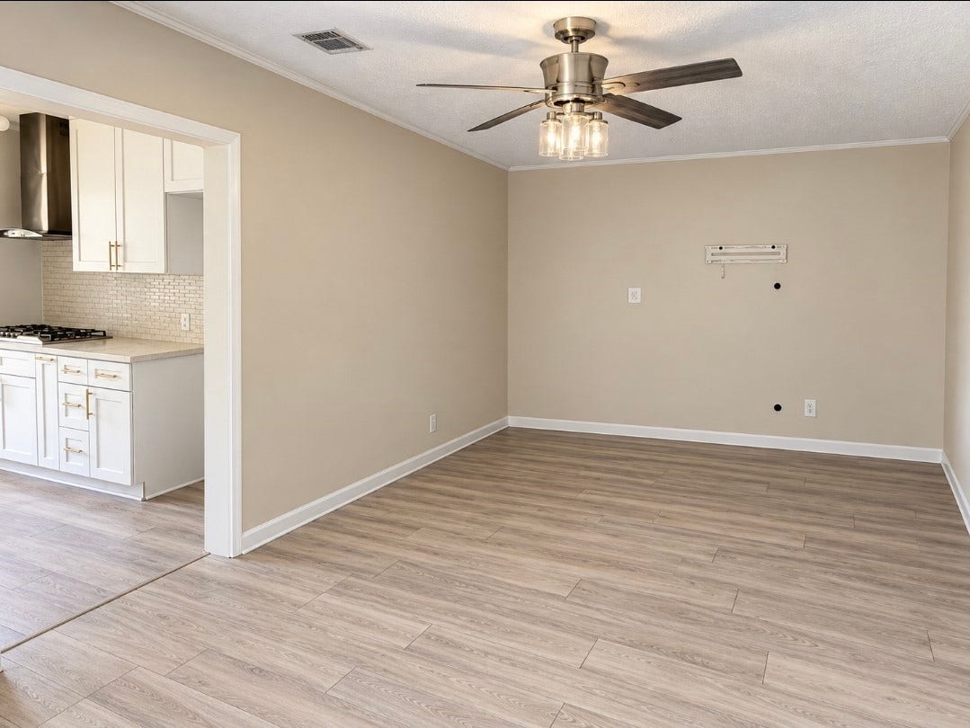 7929 Talton Street, Houston, TX 77028 Bright and inviting living space with modern wood flooring, a stylish ceiling fan, and an adjoining kitchen featuring sleek white cabinetry and stainless steel appliances.
