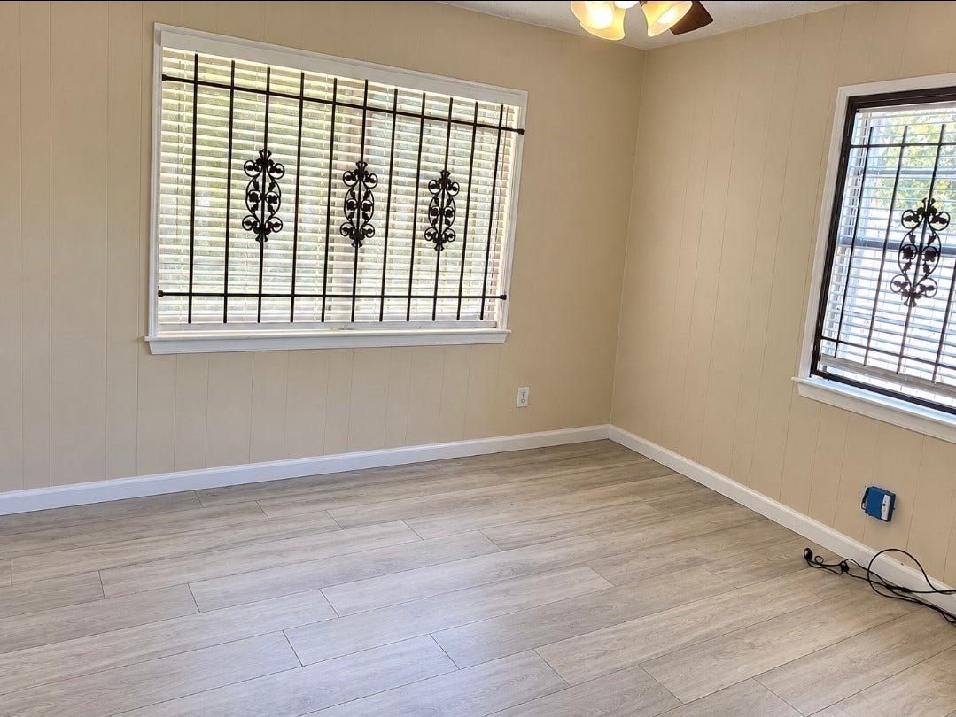 7929 Talton Street, Houston, TX 77028 Bright room with elegant metal window grilles, warm beige walls, and modern wood-look flooring, creating a cozy and inviting atmosphere.