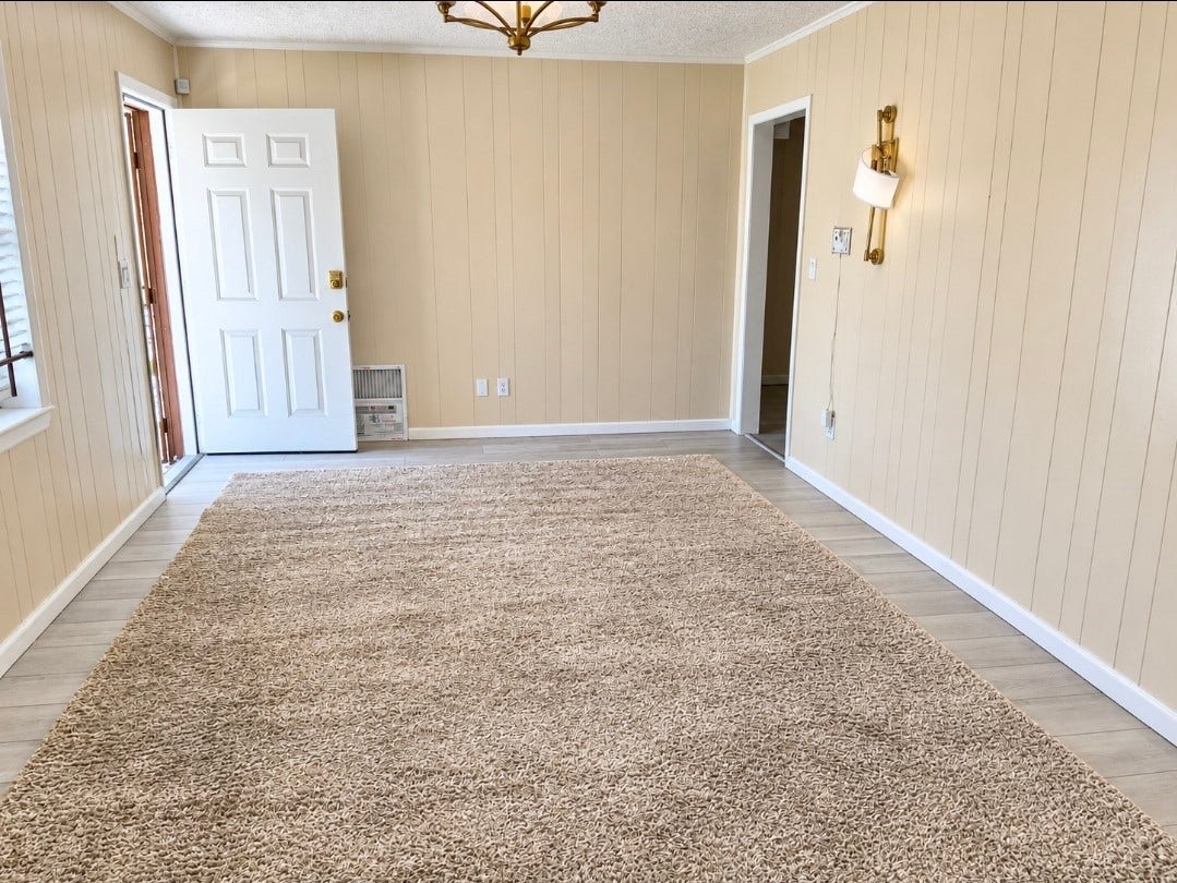7929 Talton Street, Houston, TX 77028 Bright, welcoming room with light wood-paneled walls, plush carpet, and a stylish chandelier, offering a cozy and inviting atmosphere.