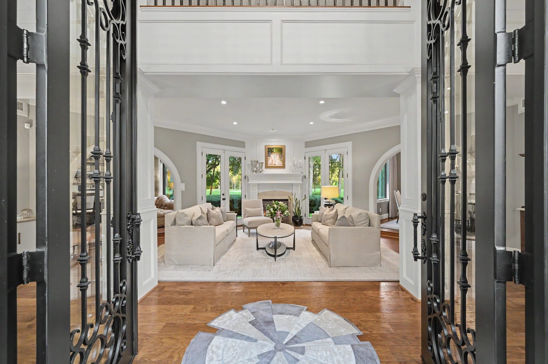 Large Cantera doors open to reveal an elegant formal living room, creating a striking first impression upon arrival.