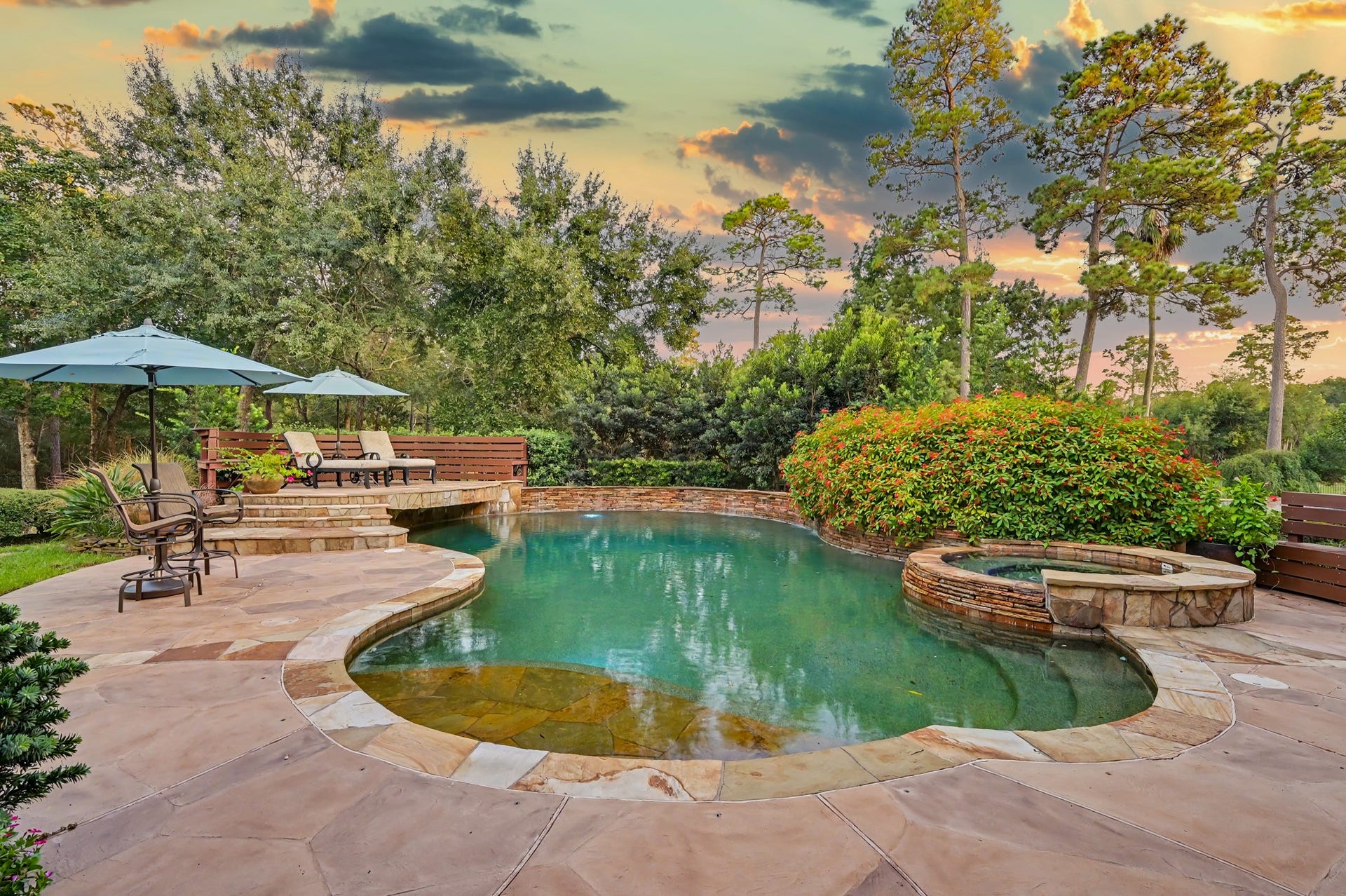 Resort style backyard that features a resort style pool and hotub with multiple areas for relaxing